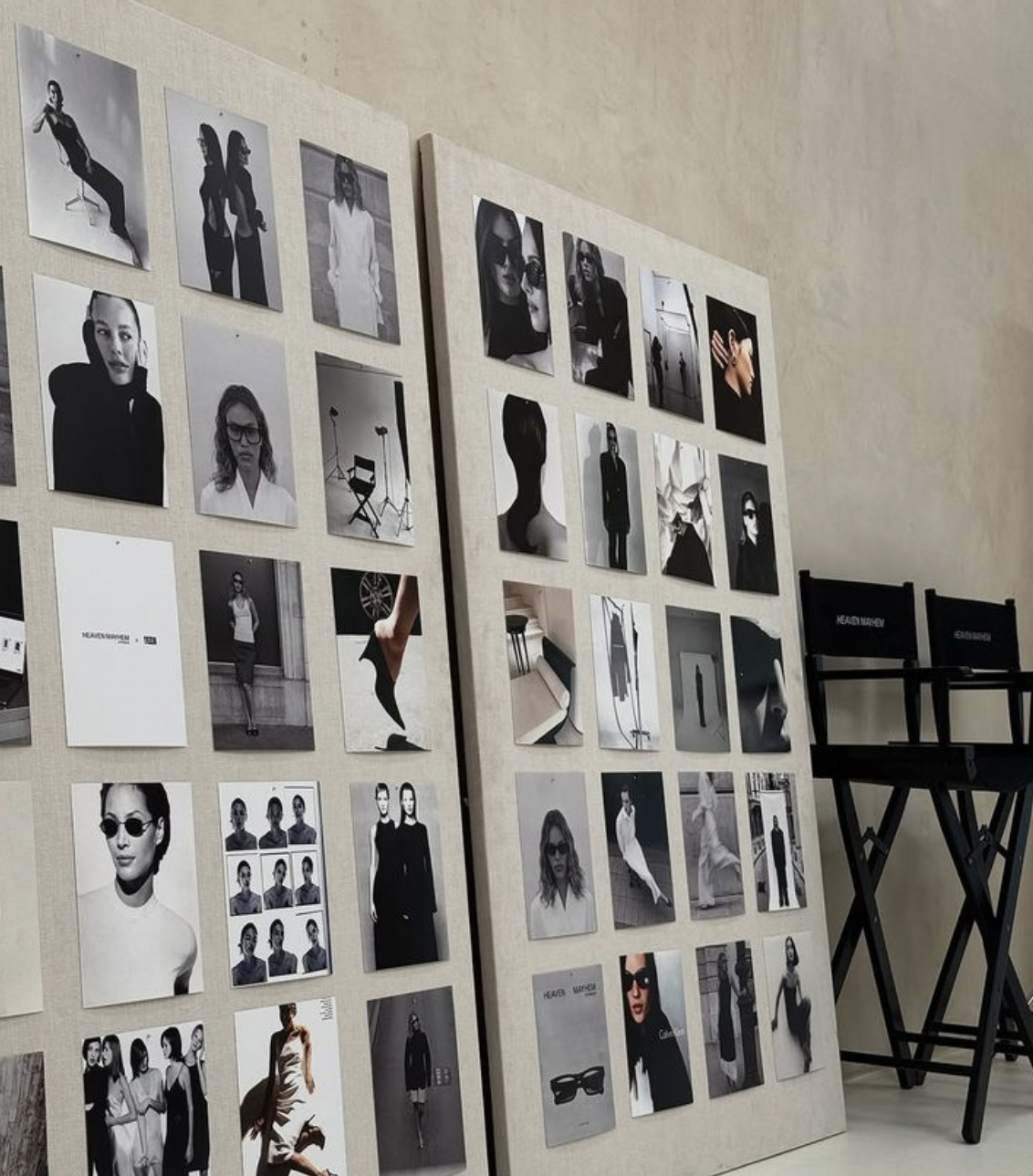 Display boards with black-and-white fashion photographs and model portraits, with two black folding chairs nearby.