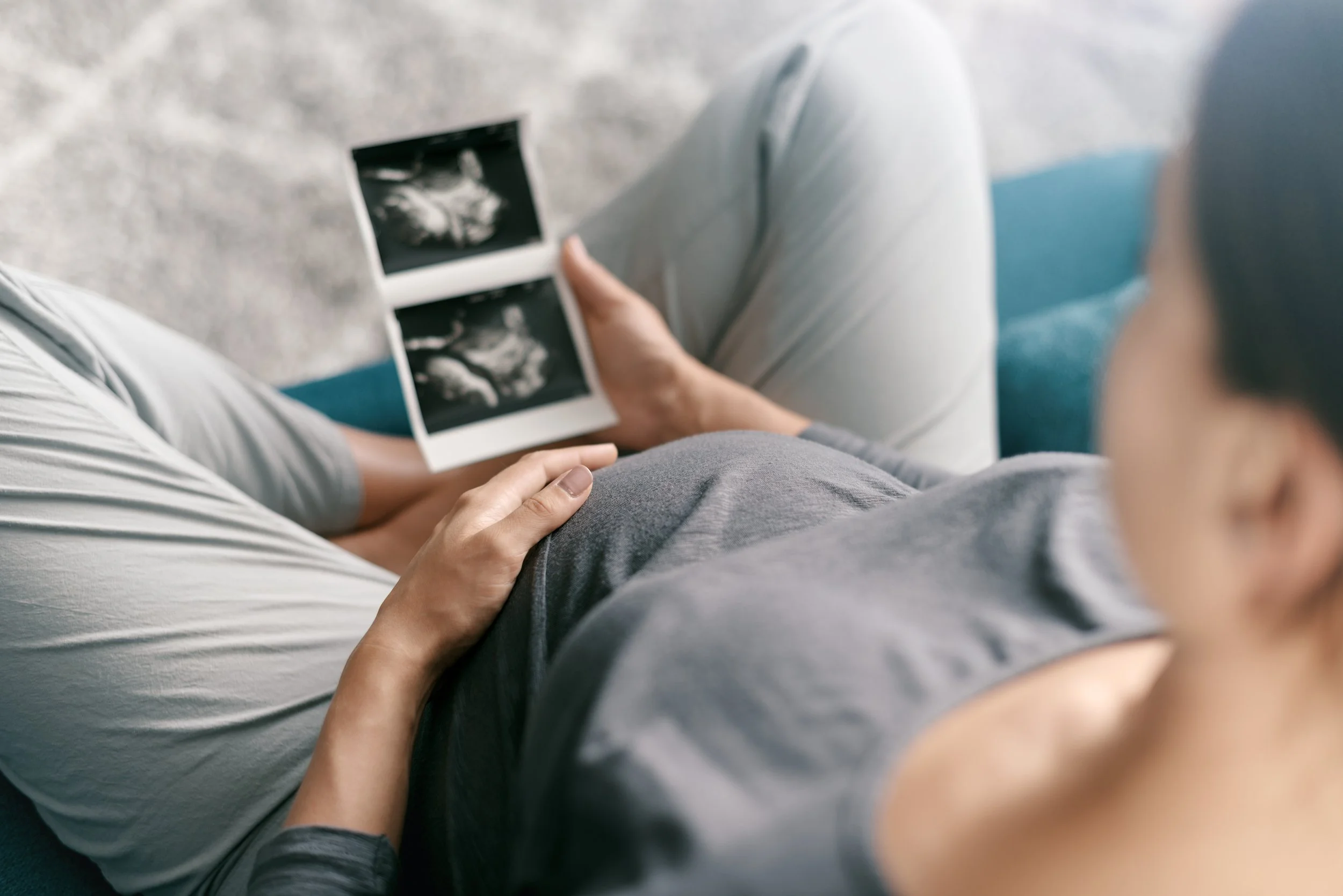Person holding ultrasound images sitting with another person.