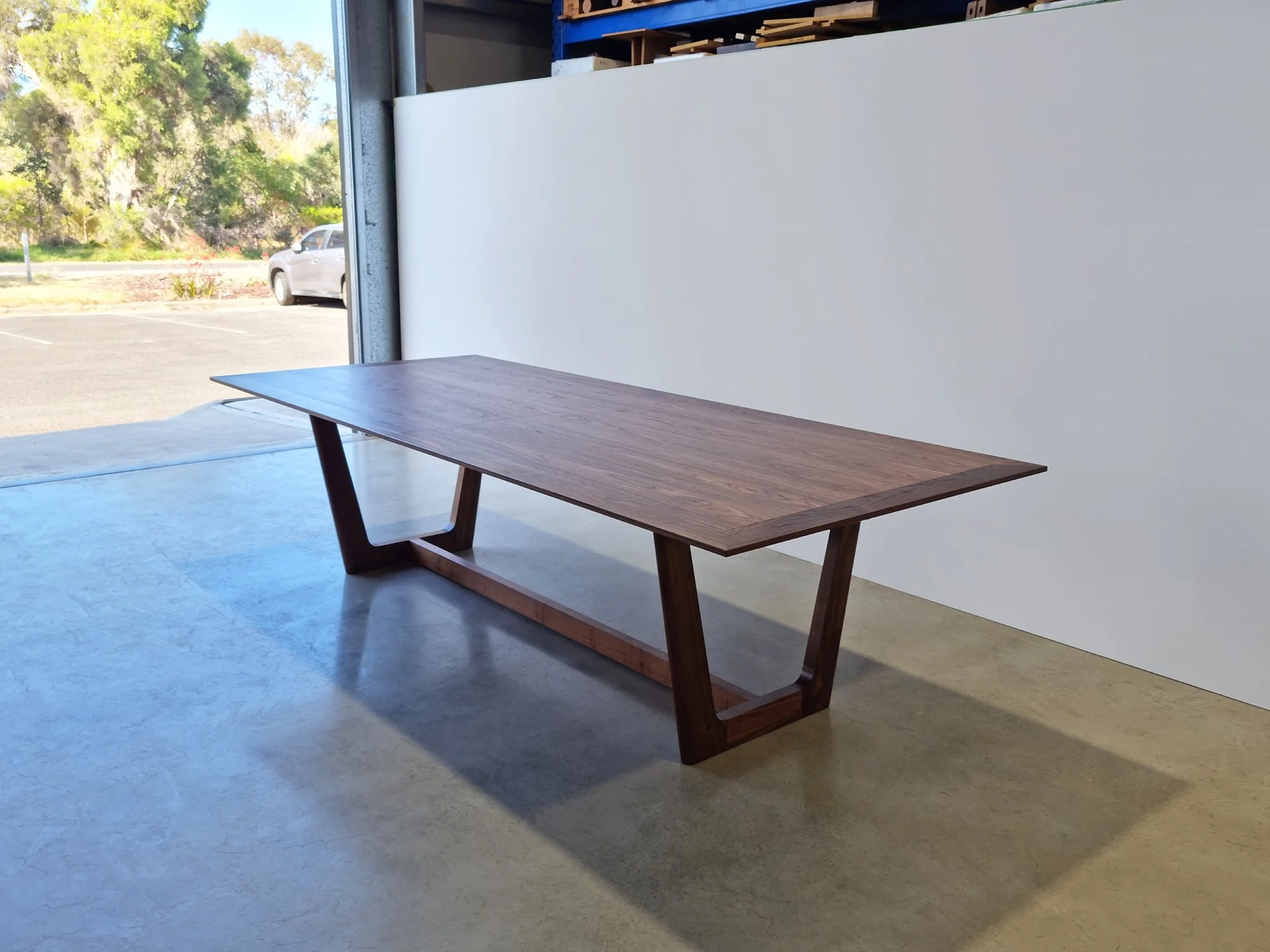 Botanical Table in Walnut, angled view near workshop doorway with carpark visible outside - bespoke furniture by Nathan Day Design