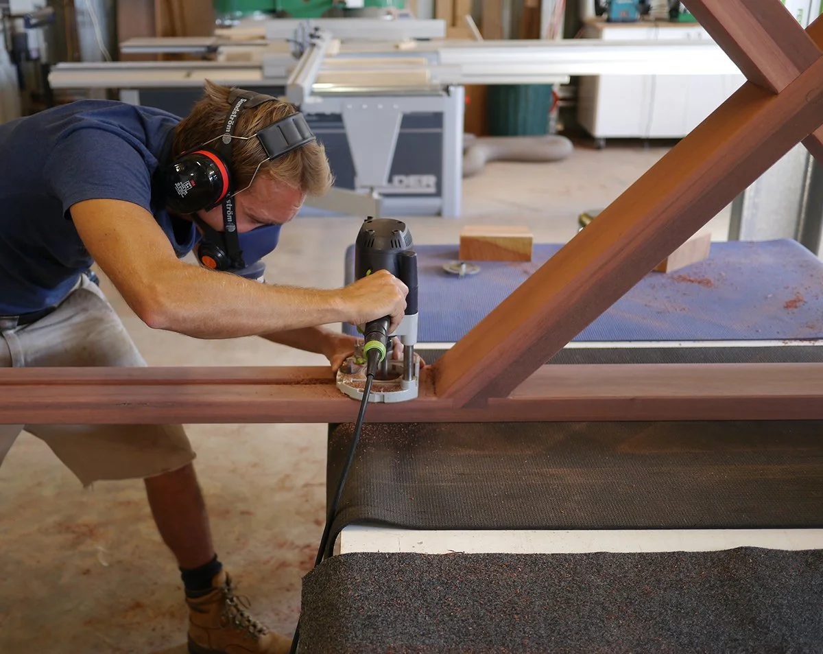 Woods Bagot Boardroom Table in ebonised Jarrah - Nathan Day Design, close-up of maker hand-finishing leg joinery in workshop