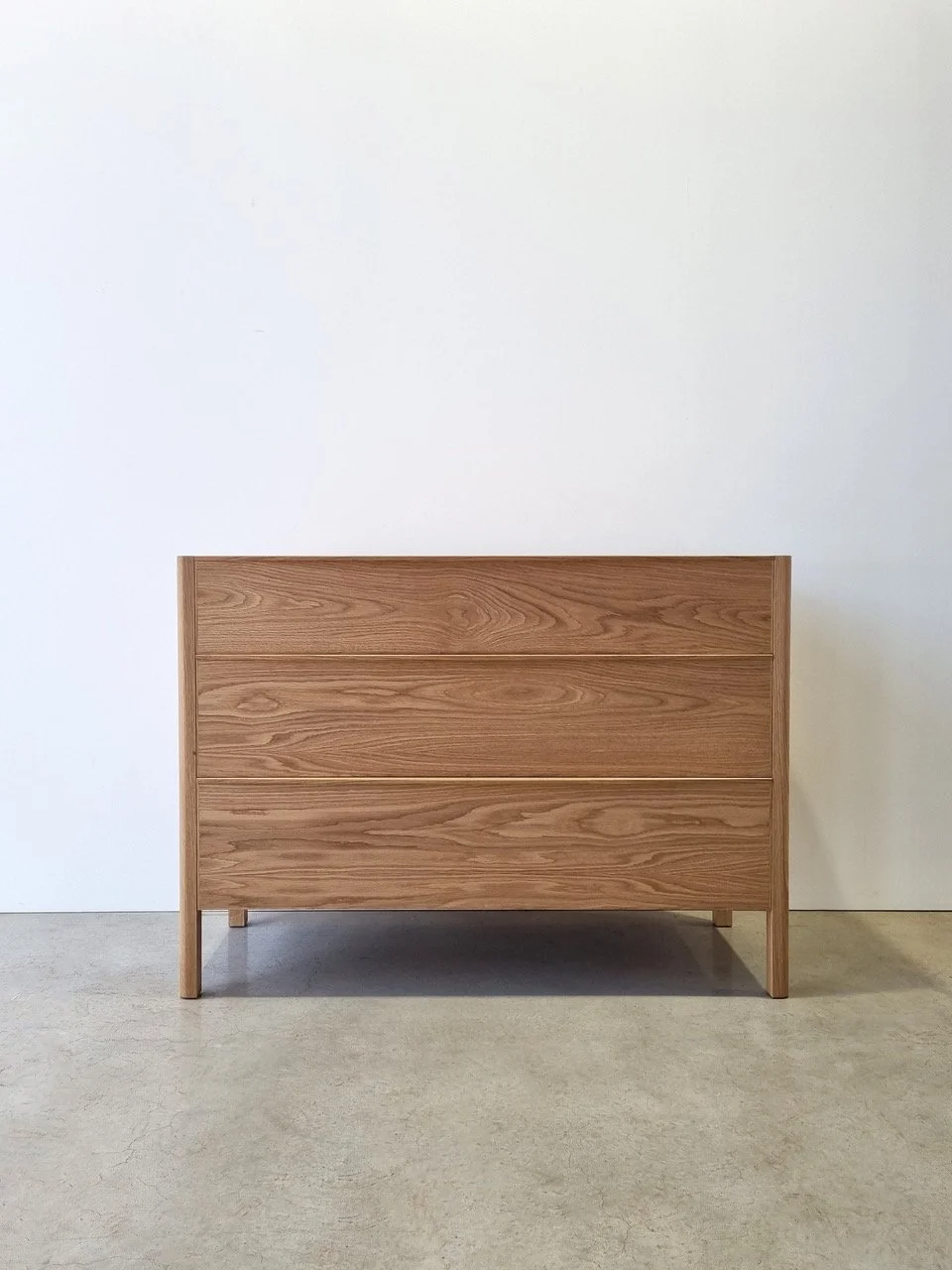 Hampden Chest of Drawers in American Oak - Nathan Day Design, front view in studio showing minimal frame-leg design