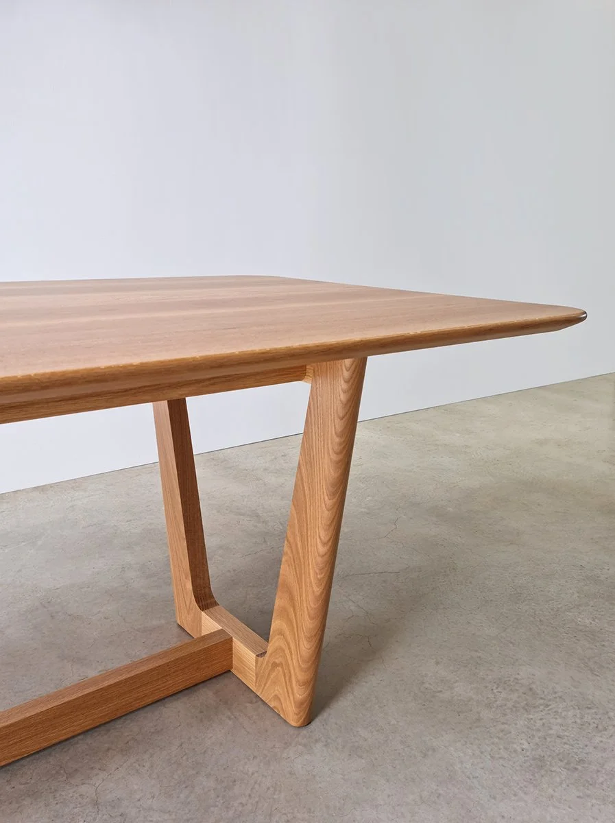 Close-up detail of Botanical Table's angled trestle leg and tabletop edge in American Oak, showing joinery and grain - bespoke furniture by Nathan Day Design