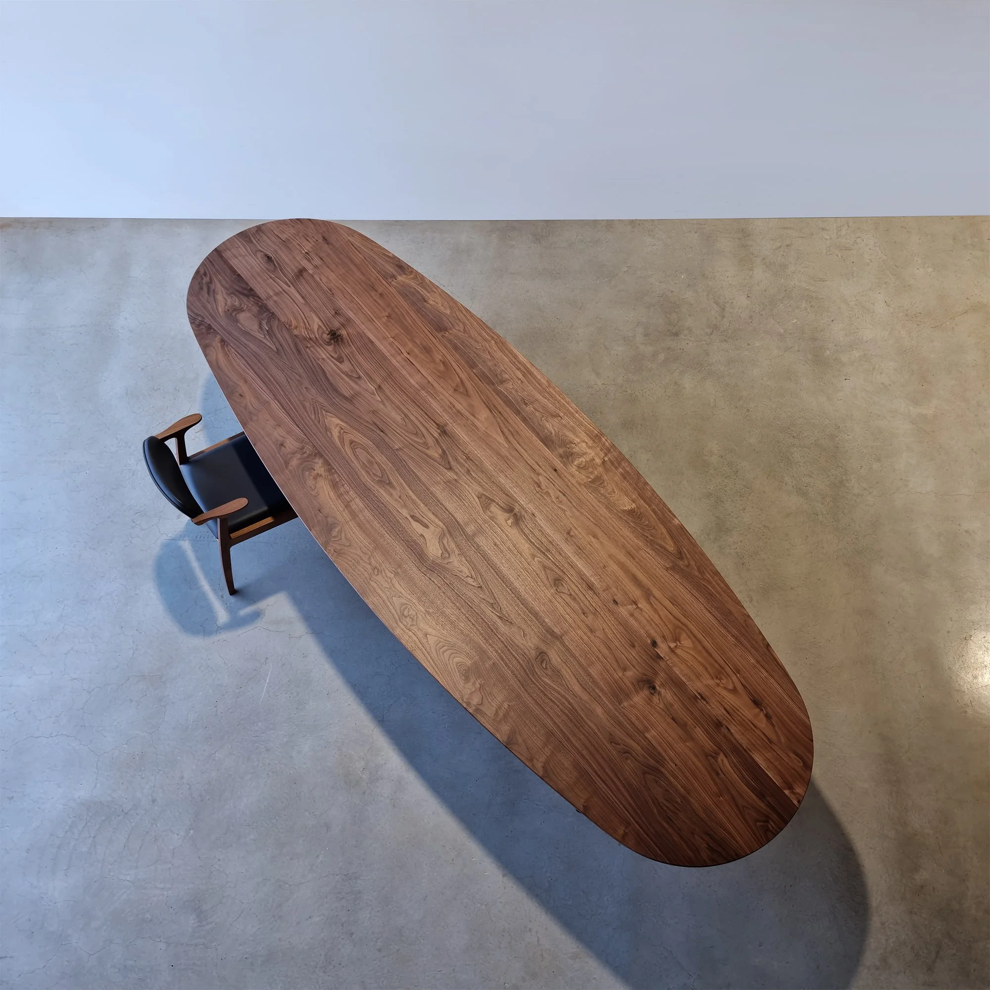 Overhead view of Peppy Grove Table's elongated oval top in Walnut showing rich timber grain - bespoke furniture by Nathan Day Design