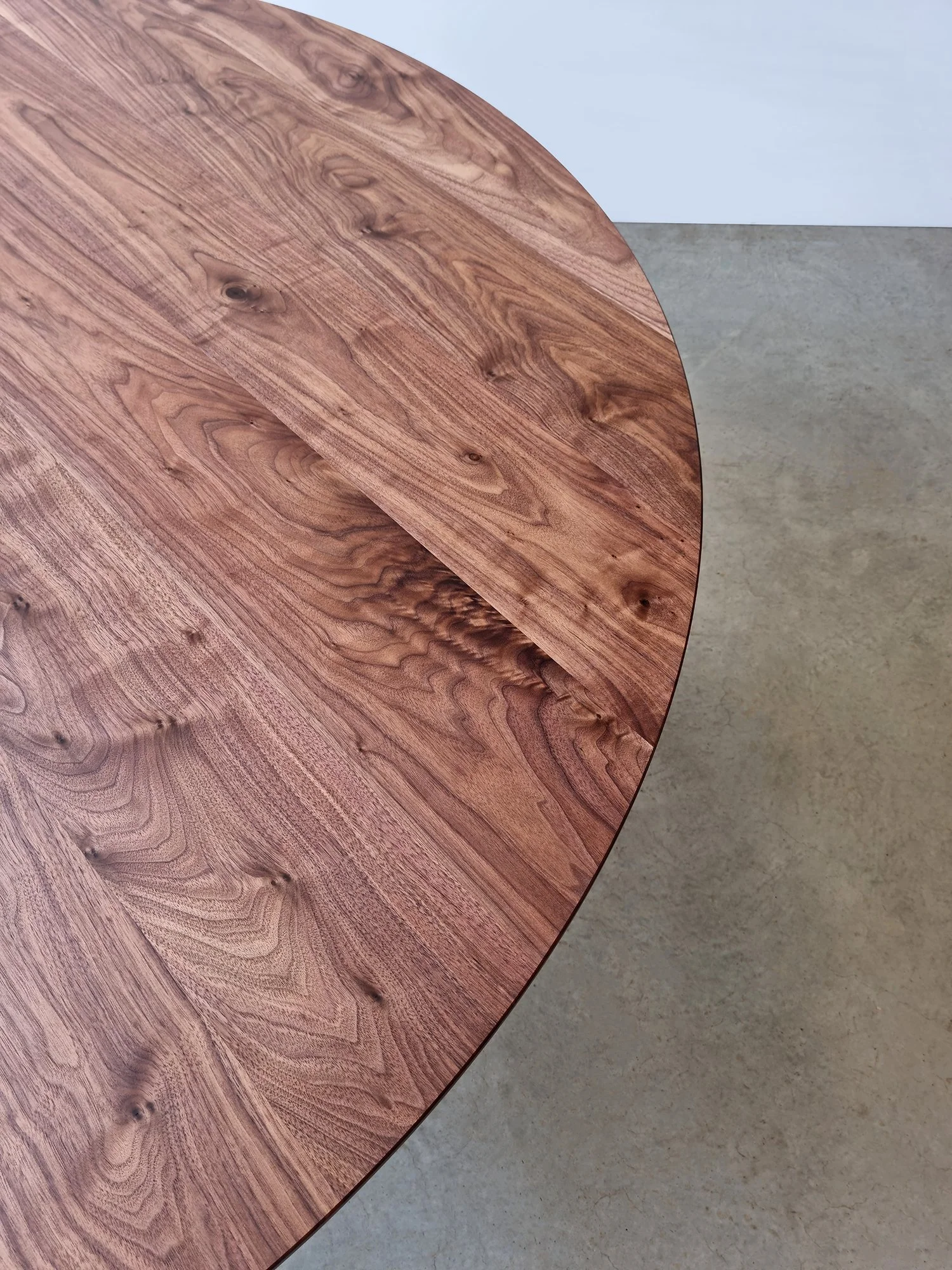 Overhead detail of the round Froxfield Table's Walnut tabletop showing its natural knots and grain - Nathan Day Design