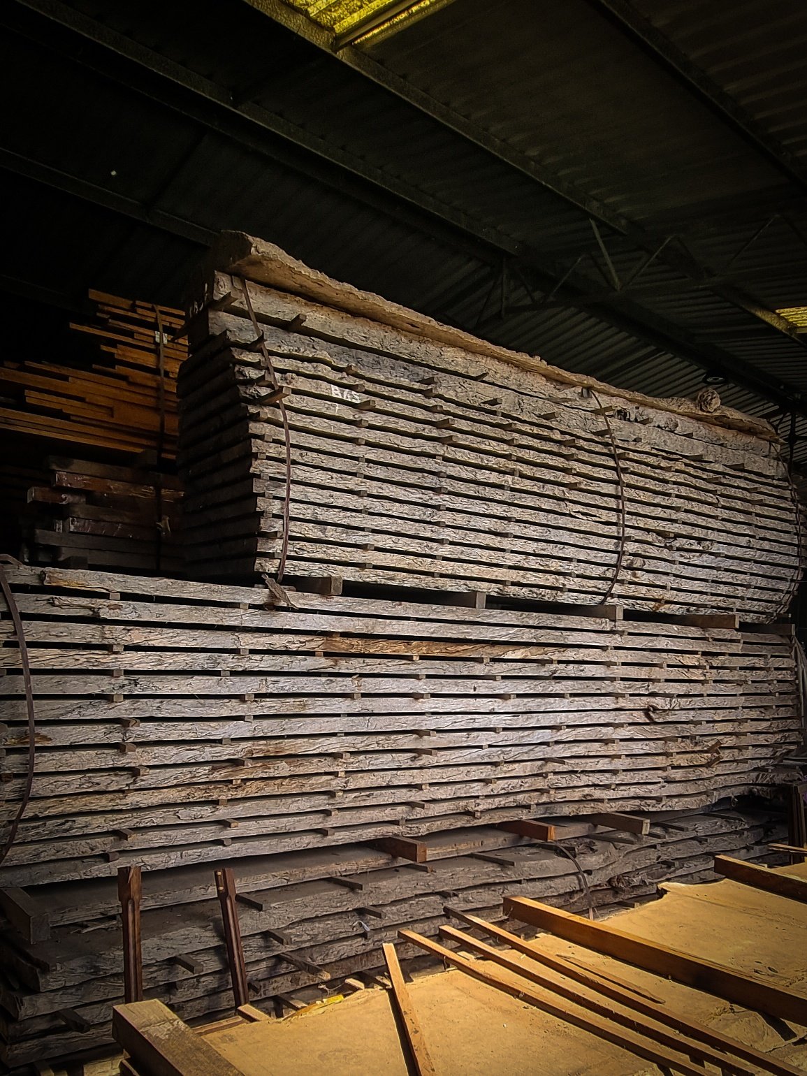 Stacked timber boards seasoning in the Nathan Day Design workshop, ready for use in bespoke furniture