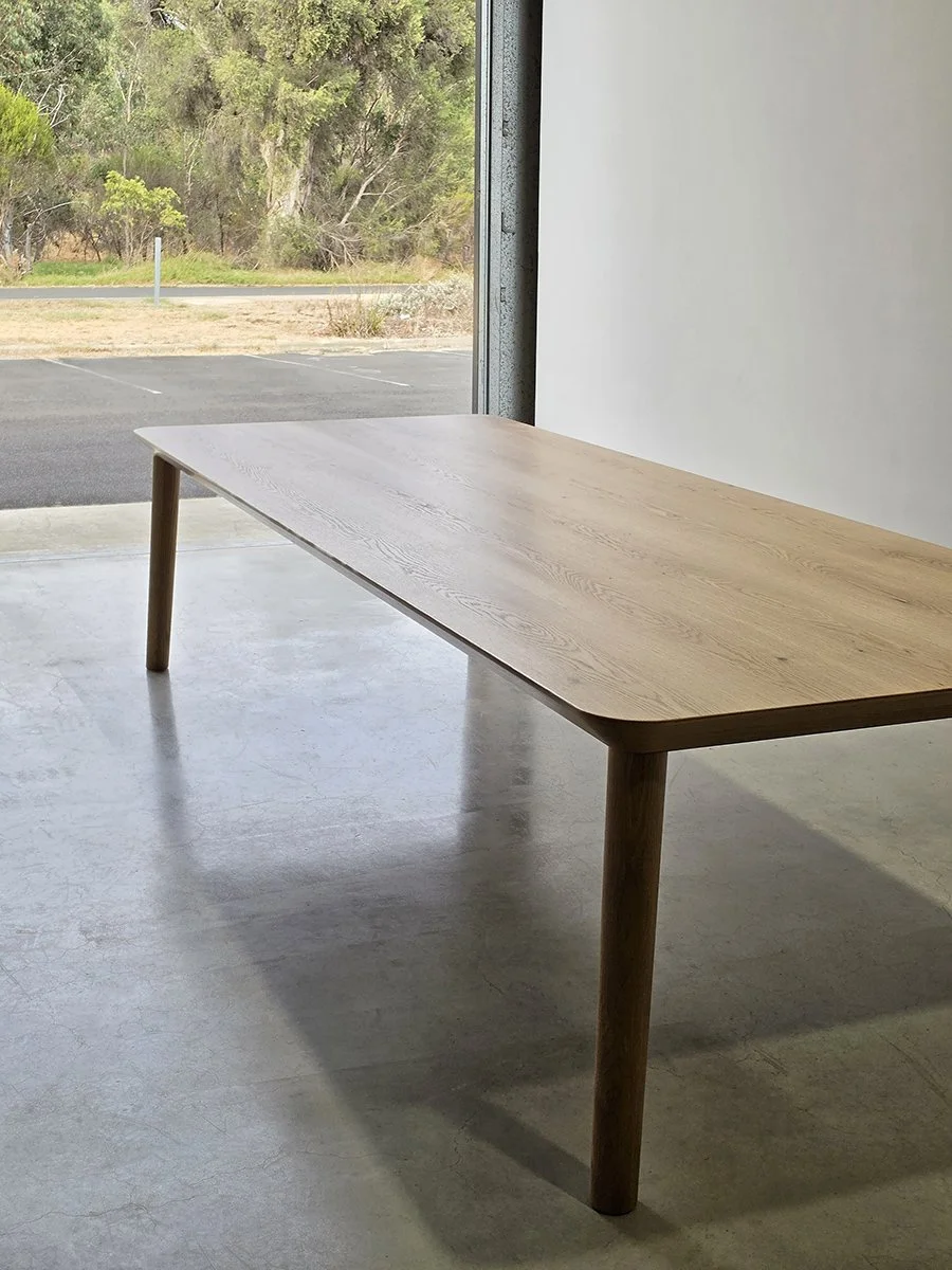 Mercator Way Table in American Oak positioned near open workshop doorway with bushland view beyond - bespoke furniture by Nathan Day Design