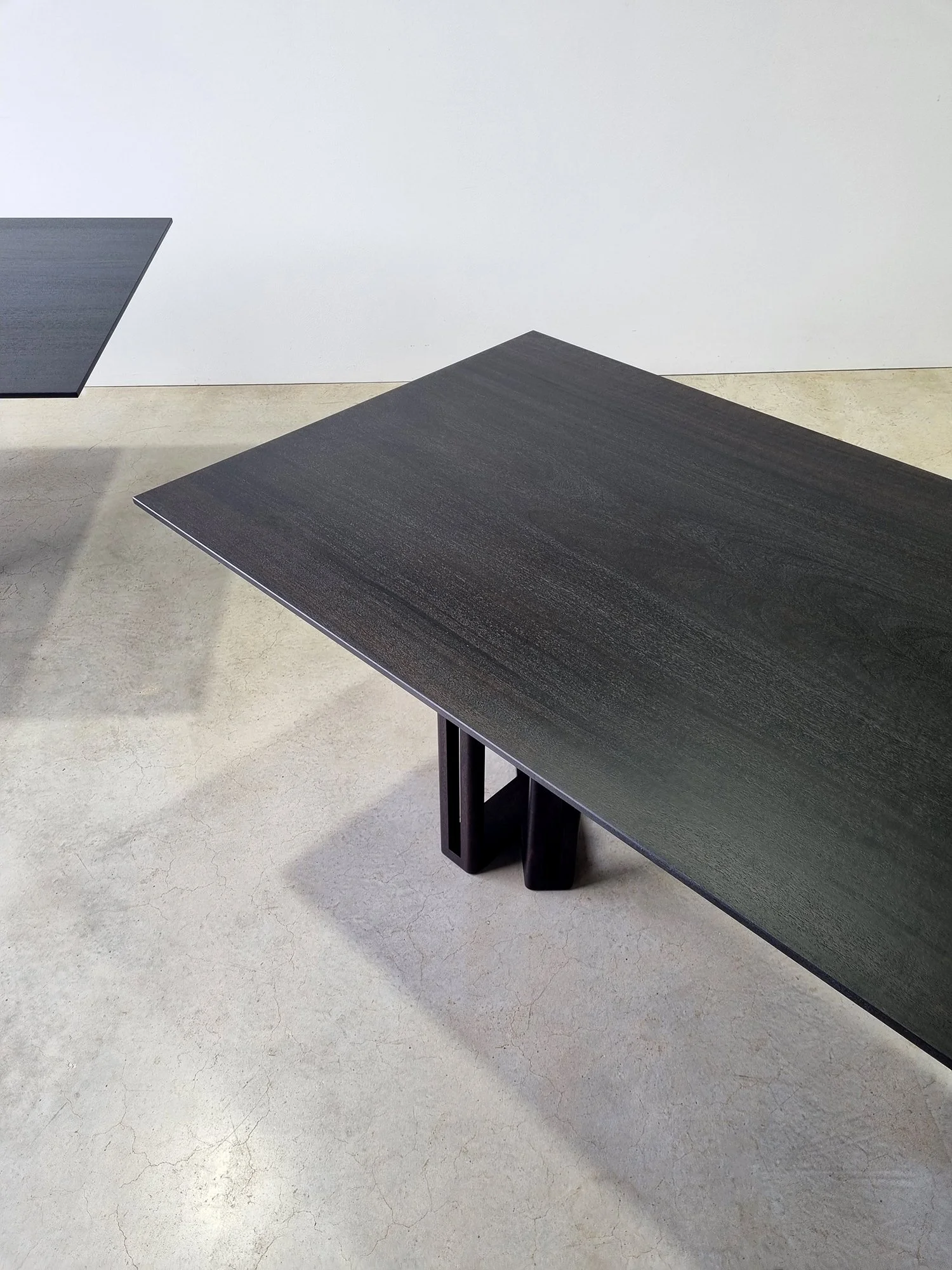Overhead angled view of the Giacci Table's Y-leg detail, a matching console table visible behind - Nathan Day Design
