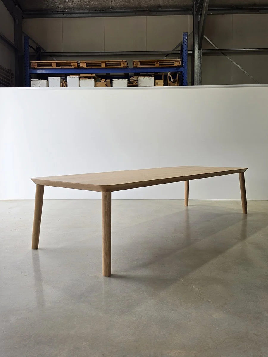 Elevated three-quarter view of Mercator Way Table in American Oak showing full tabletop surface and grain, workshop setting - bespoke furniture by Nathan Day Design
