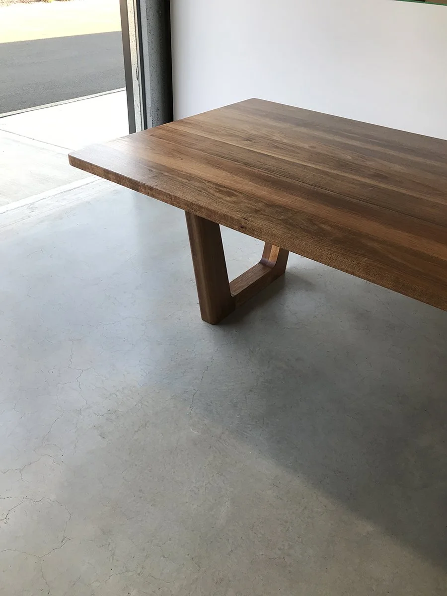 Corner detail of Clairault Table in Walnut showing trapezoidal leg frame joinery, near workshop doorway - bespoke furniture by Nathan Day Design