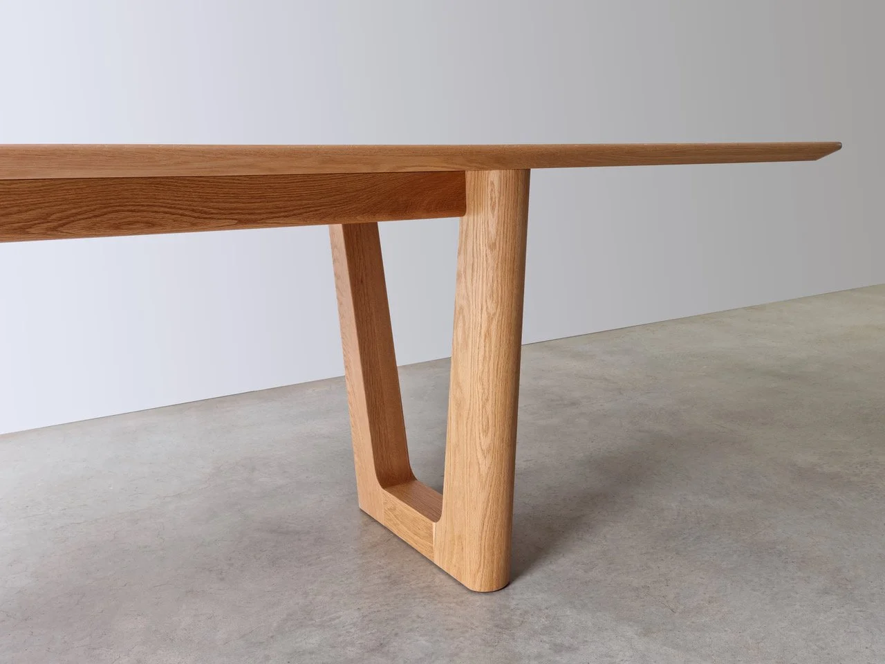 Close-up of Aalia Table's distinctive V-shaped angled leg joinery in American Oak - bespoke furniture by Nathan Day Design