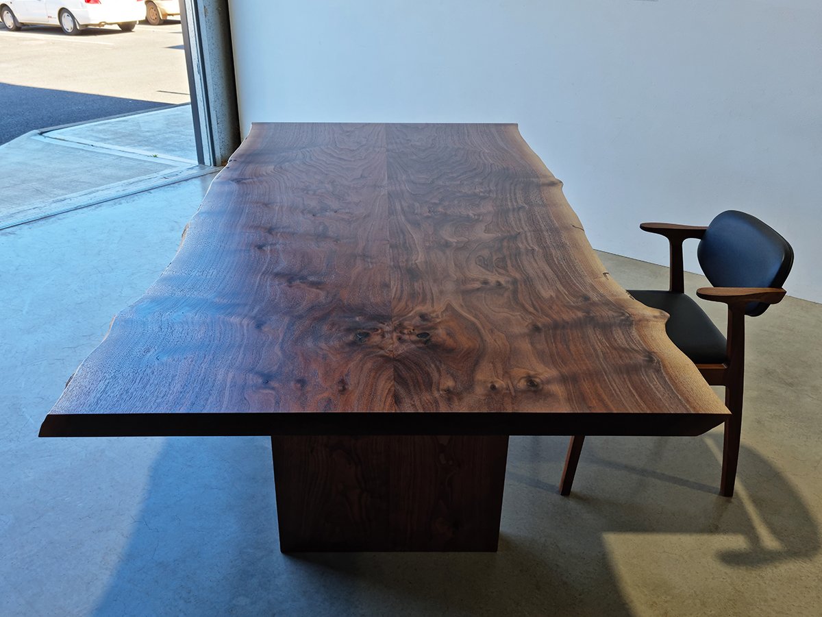Live edge dining table in richly figured Marri showing dramatic burl grain, paired with a leather dining chair - bespoke furniture by Nathan Day Design