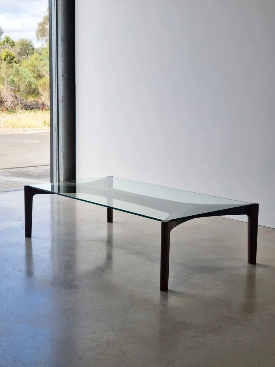 Wende Coffee Table in dark walnut finish, styled in a gallery space with glass doors - bespoke furniture by Nathan Day Design