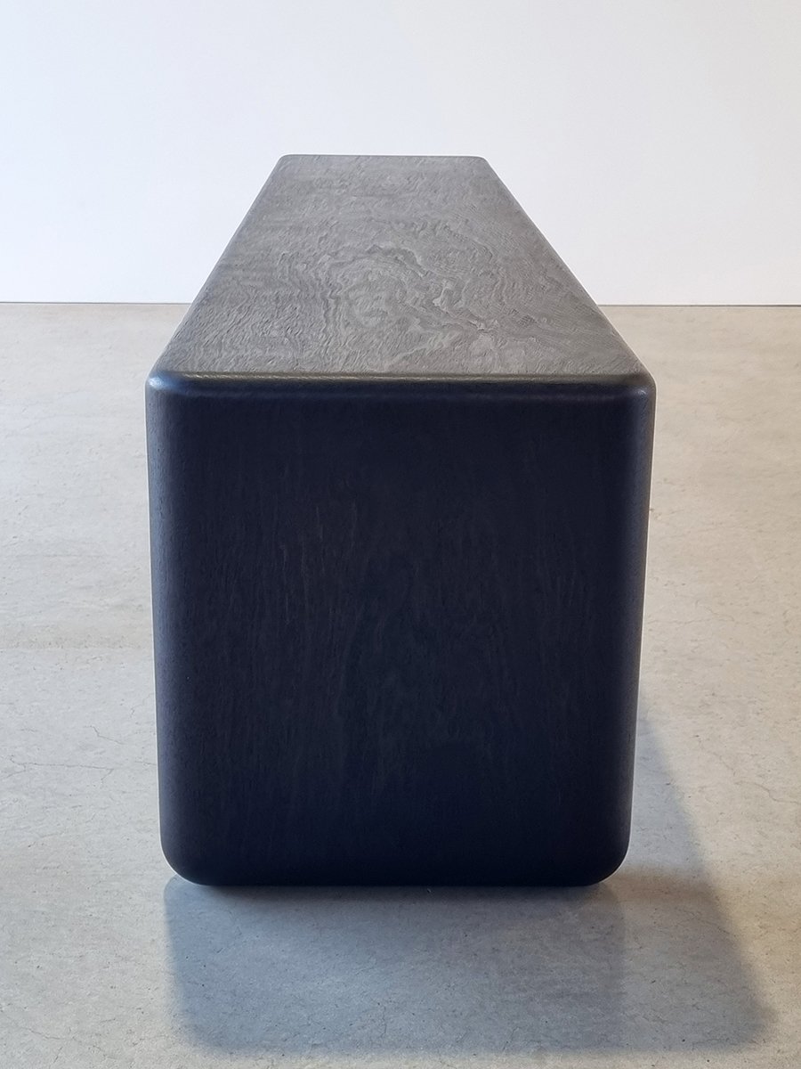 End-on view of Hippo Bench in Ebonised Jarrah showing the full rounded end profile and heavy proportions - bespoke seating by Nathan Day Design