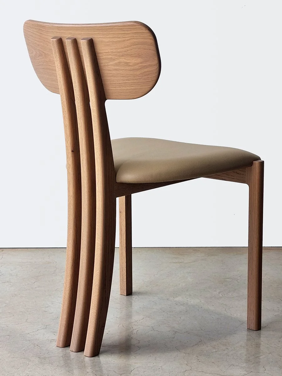 Tulip Chair in American Oak with vertical slat back and tan leather seat, angled rear view in plain studio setting - bespoke furniture by Nathan Day Design