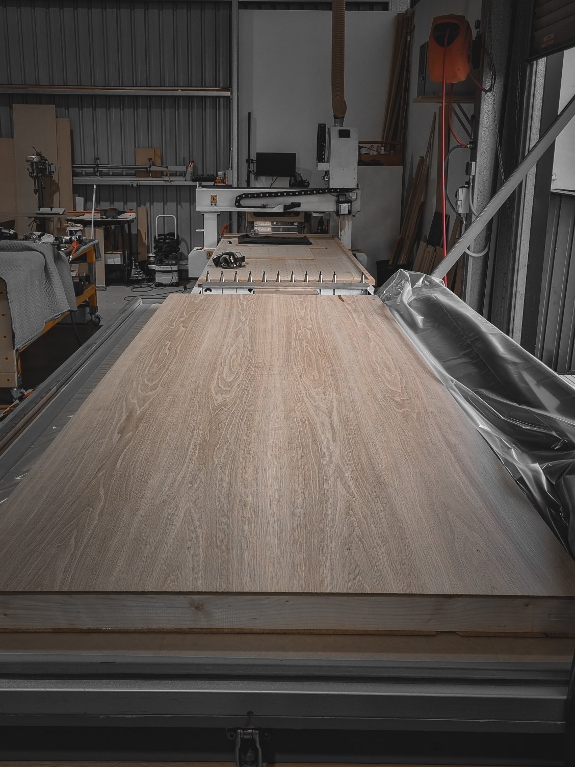 Wide shot of a long timber tabletop laid out on the workshop floor during fabrication at Nathan Day Design