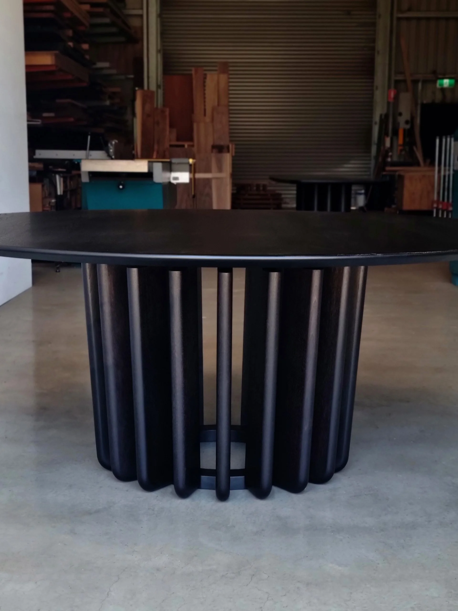 Front-on workshop view of the Lantern Table's ebonised fin base with cross-brace visible through the gaps - Nathan Day Design