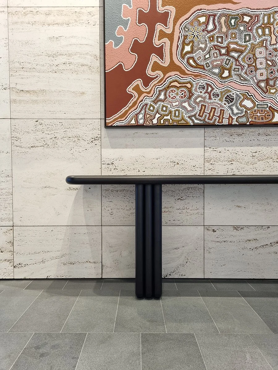 Walters Lobby Console in ebonised Walnut, angled view of cross-leg base in lobby setting - Nathan Day Design