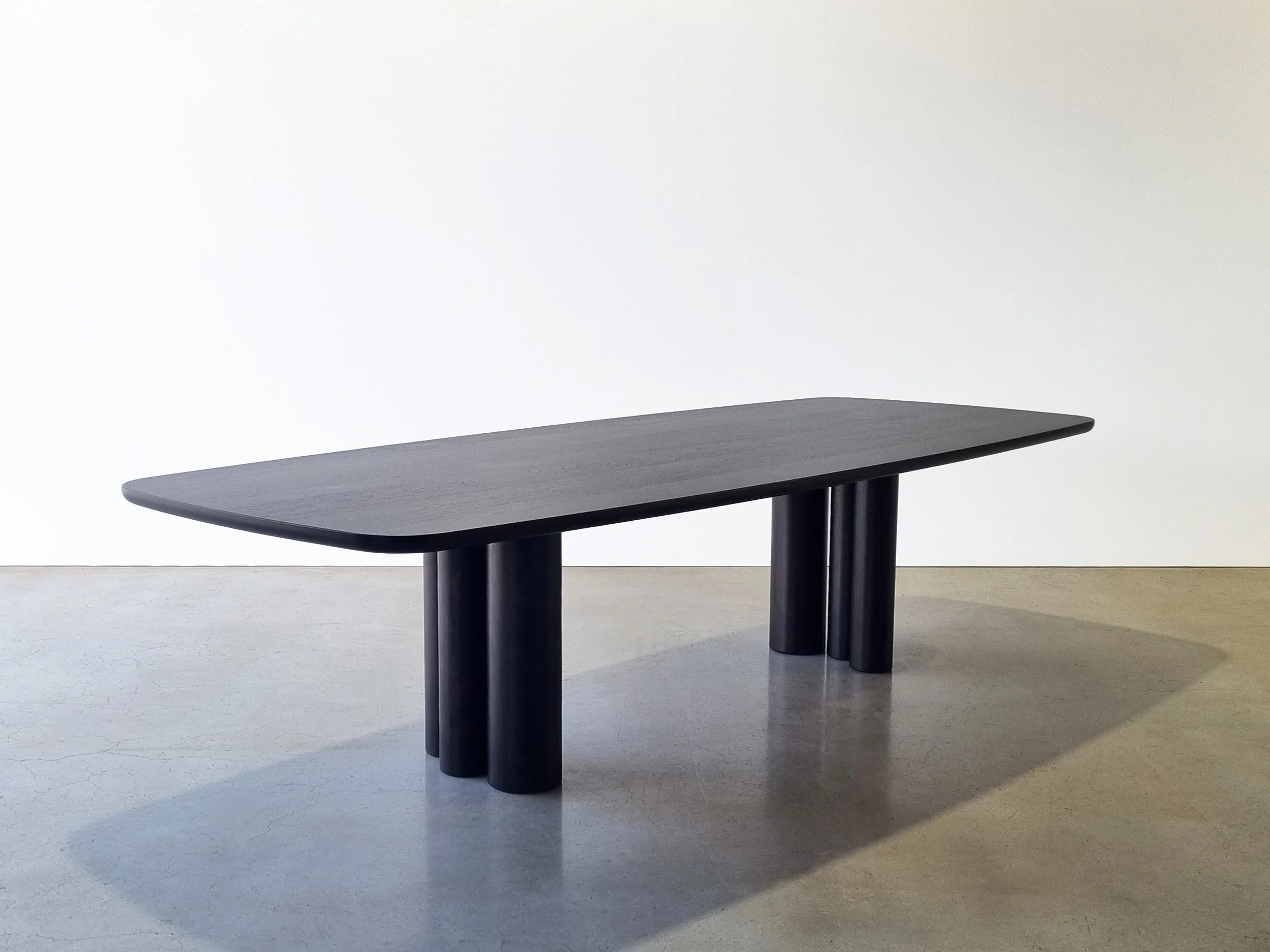 Angled three-quarter view of Column Table in Ebonised Walnut showing asymmetrical arrangement of cylindrical legs - bespoke furniture by Nathan Day Design