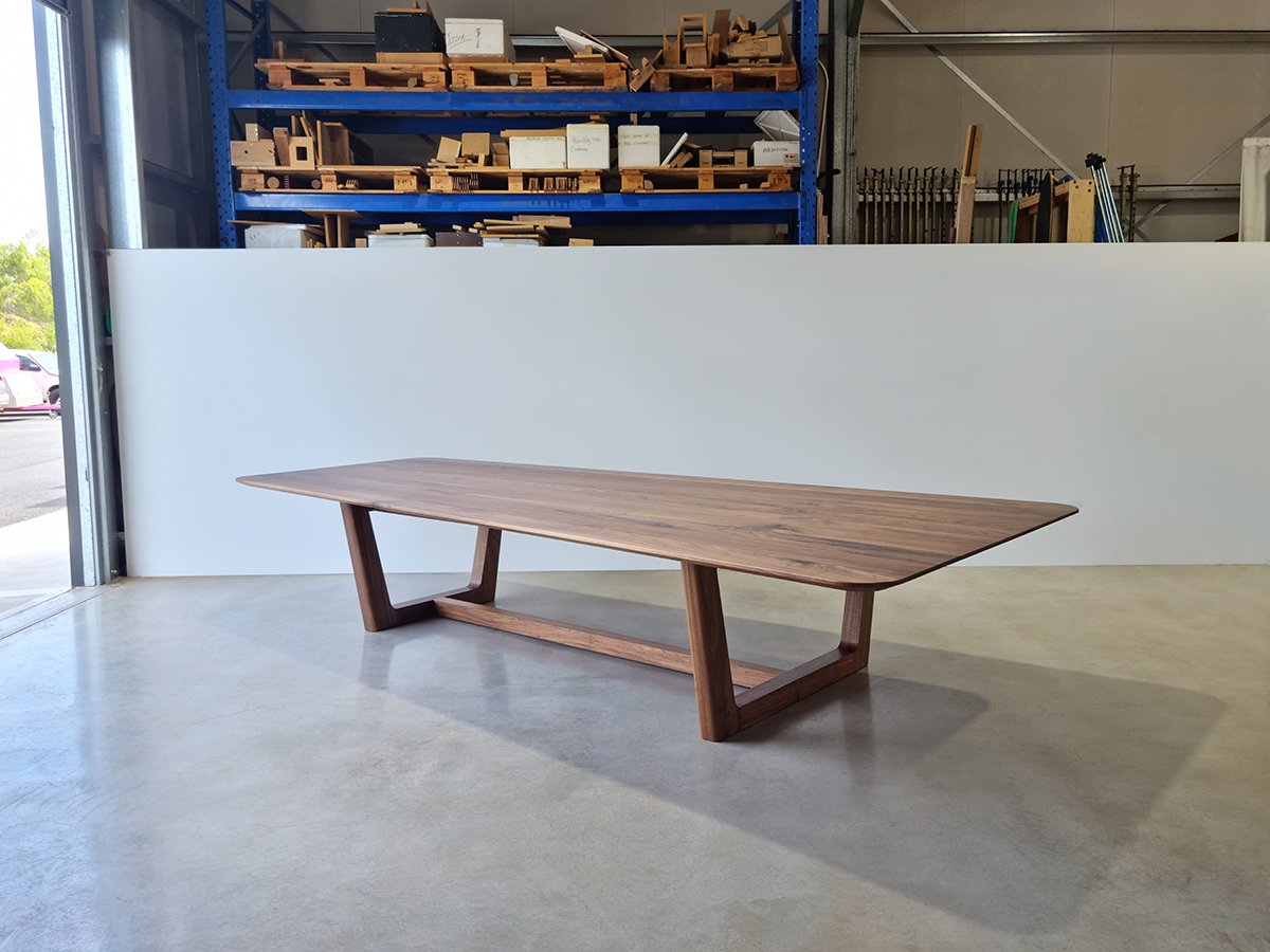 Cabarita Rd Table in American Walnut with unusual tapered shape, front-on view in workshop setting - bespoke dining table by Nathan Day Design