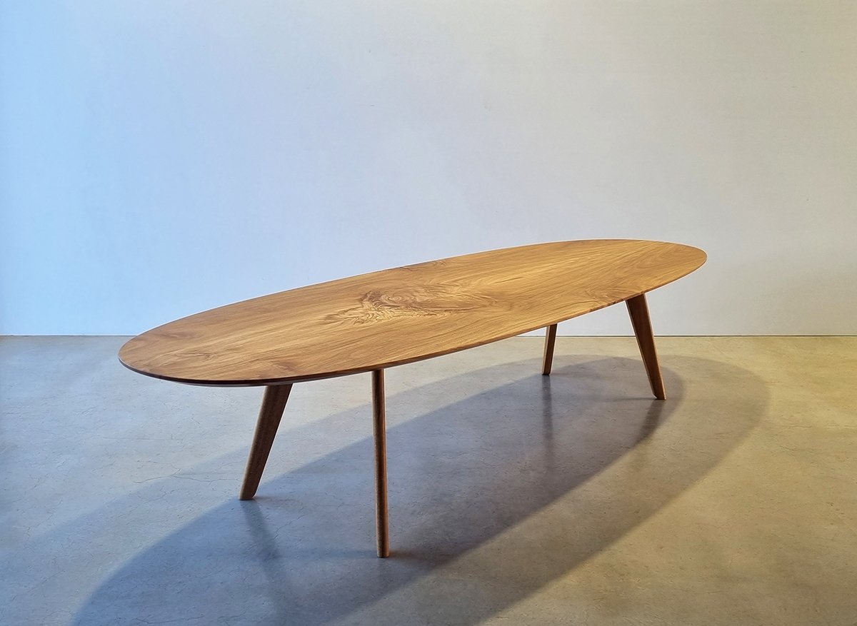 Peppy Grove Table in French Oak with elongated oval top and tapered legs, plain studio setting - bespoke furniture by Nathan Day Design