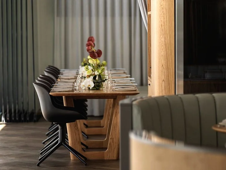 Aalia Table in Oak fully set for dining at Aalia Restaurant Sydney with black chairs, floral centrepiece and moody green interior - bespoke furniture by Nathan Day Design
