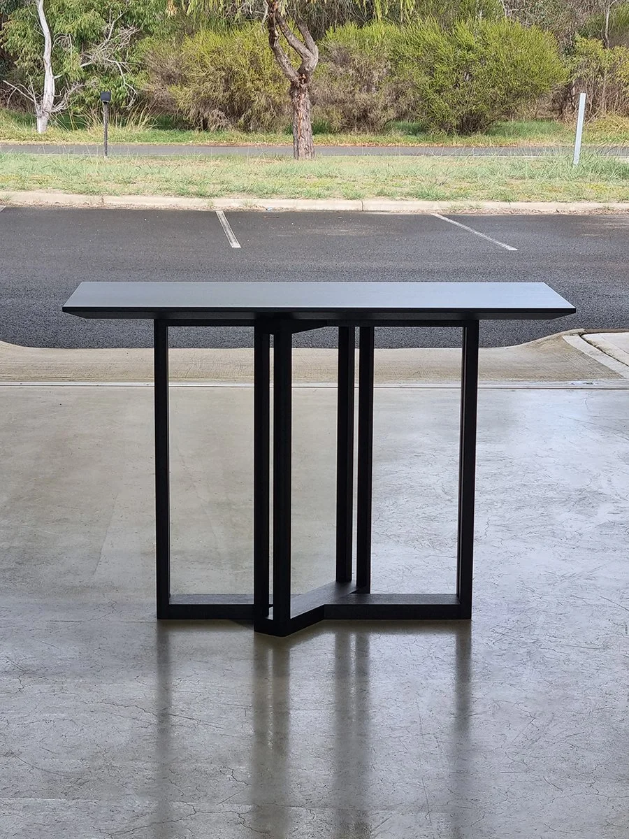 Giacci Console Table in ebonised Jarrah, geometric cross-leg base design, outdoor lifestyle setting - Nathan Day Design