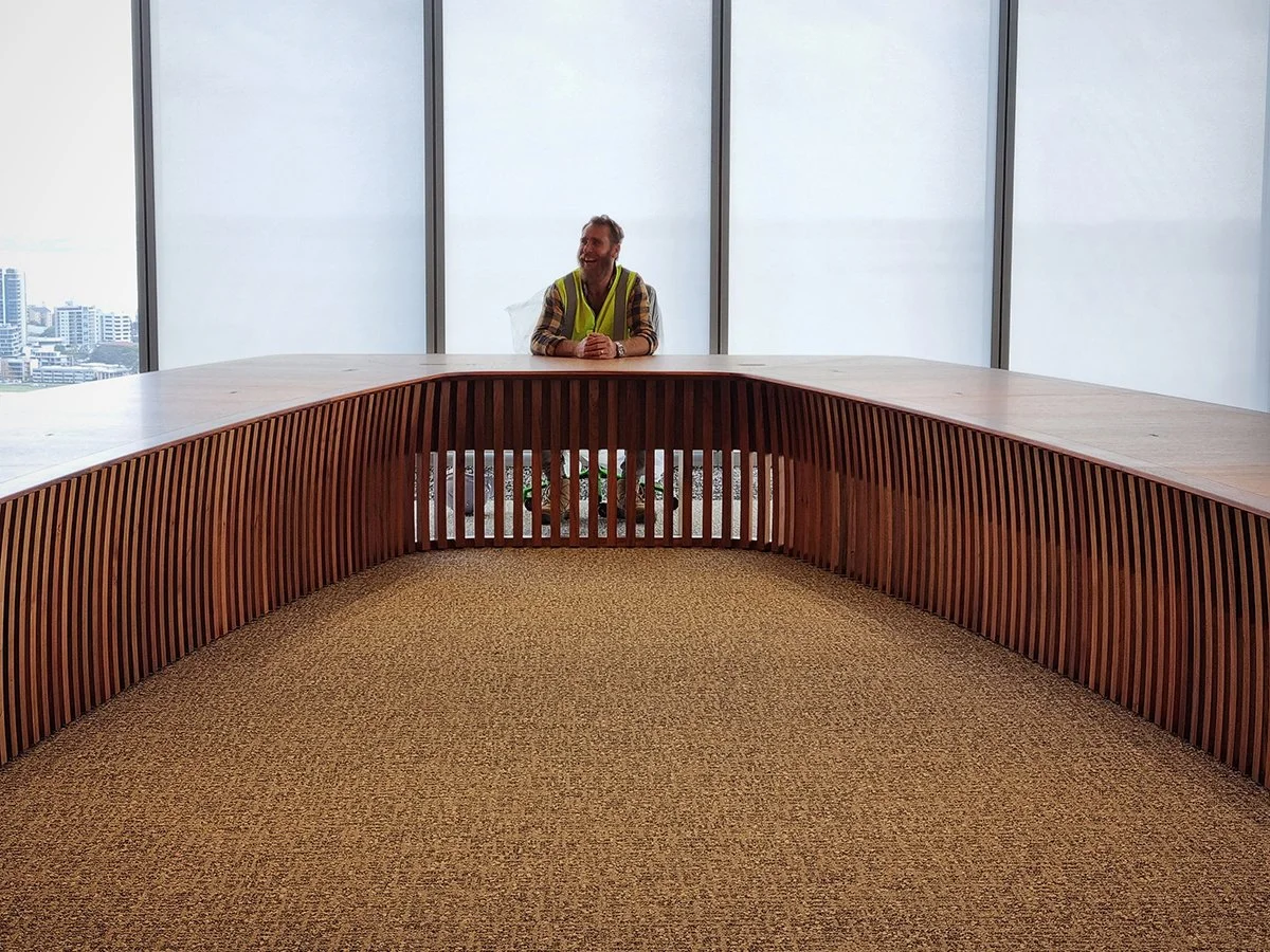 One - The Esplanade Boardroom Table in Australian Blackwood, fluted leg design - Nathan Day Design, lifestyle shot with person seated at head of table against ocean view windows