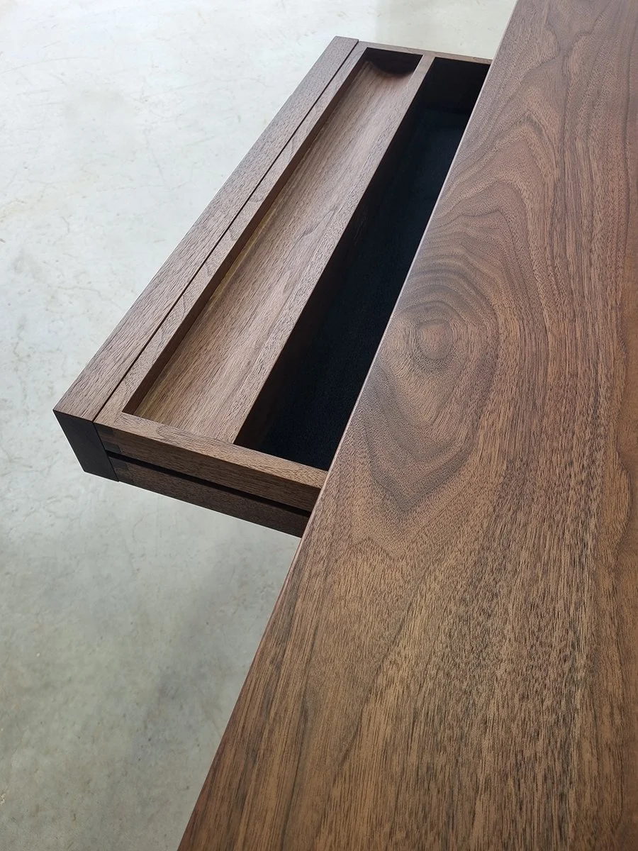 Irvine Desk in Walnut, minimalist frame-leg design - Nathan Day Design, angled view of hidden top drawer open