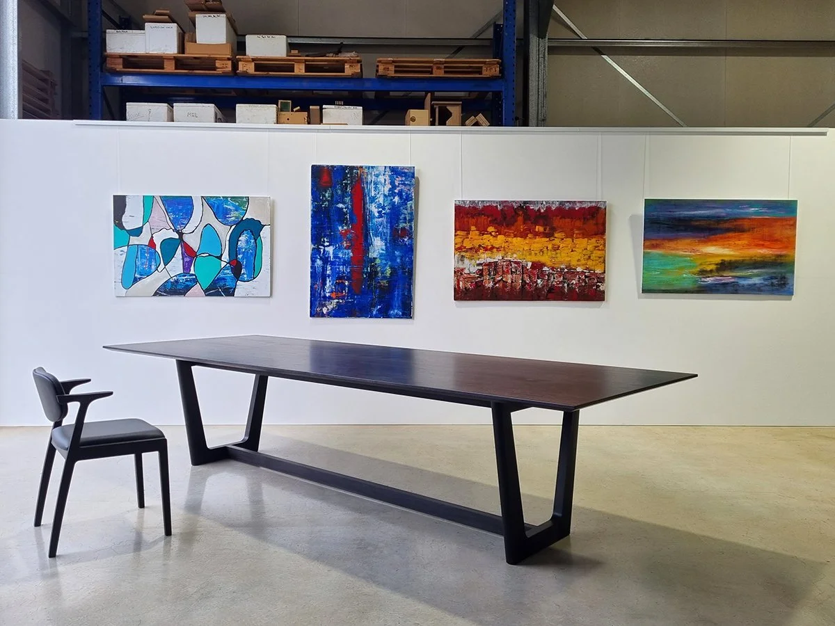 Botanical Table in ebonised black timber with matching dark chair, workshop gallery wall of abstract artworks in background - bespoke furniture by Nathan Day Design