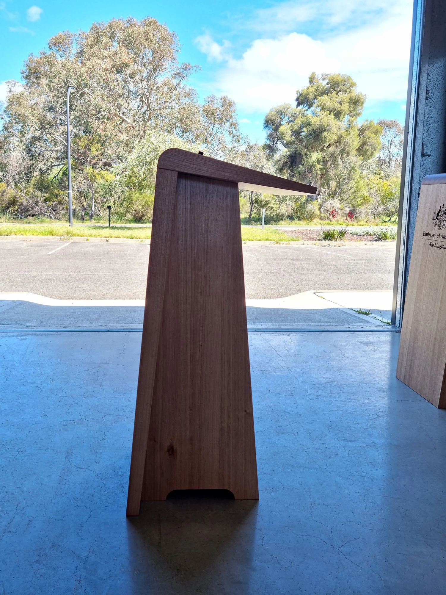 Australian Embassy Lecterns in Tasmanian Oak - Nathan Day Design, single tall angular lectern shown outdoors on paved courtyard