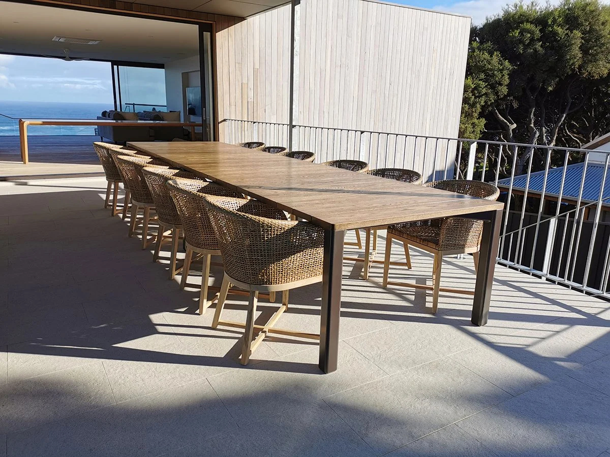 Wardanup Outdoor Table in American Oak - Nathan Day Design, full table set with woven dining chairs on covered ocean-view terrace