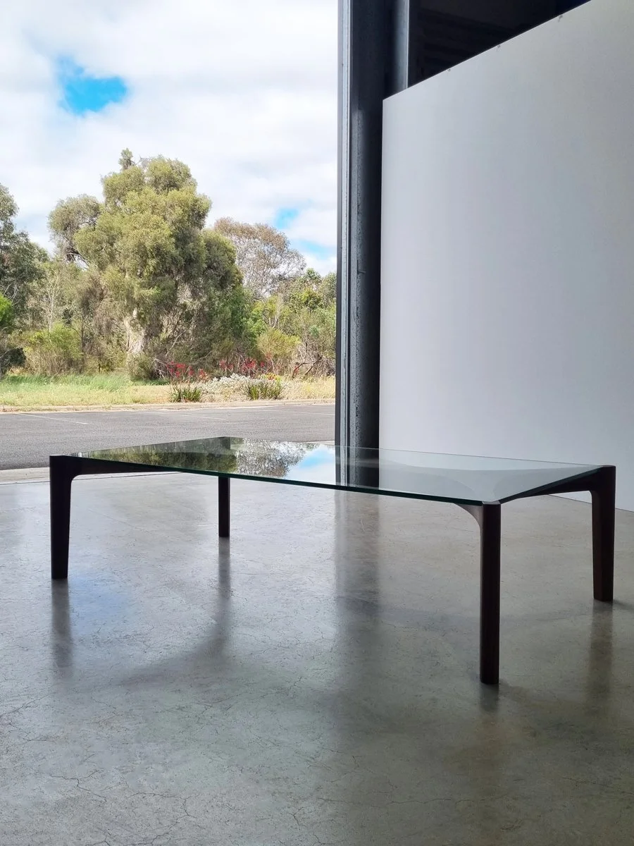Wende Coffee Table in dark walnut, wide shot in a gallery space overlooking native bushland - Nathan Day Design