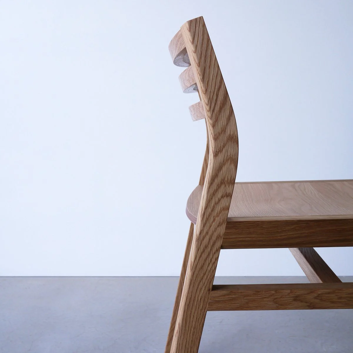 Close angled rear view of Walter Dining Chair in American Oak showing the joinery where the backrest slats meet the frame - bespoke furniture by Nathan Day Design