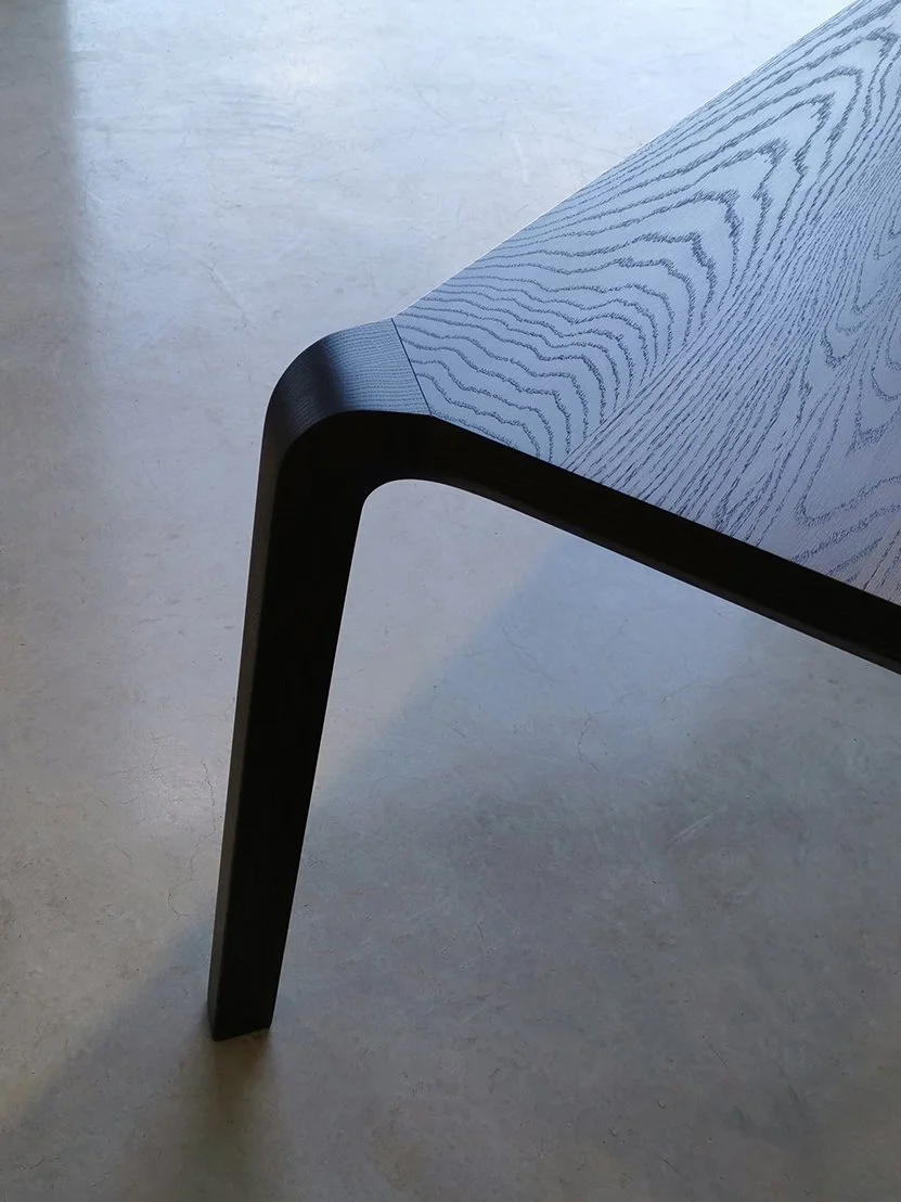Detail of the Araluen Table's corner leg in ebonised American Oak, curved joint against the tabletop grain - Nathan Day Design