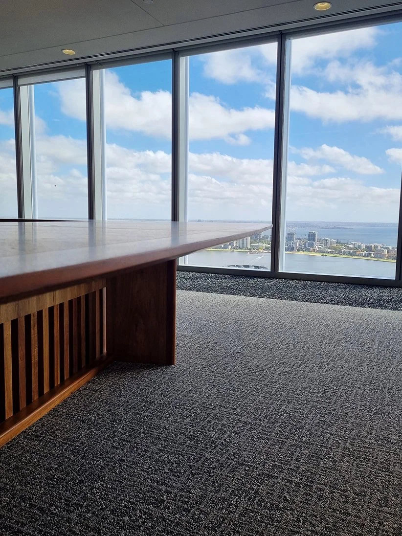 One - The Esplanade Boardroom Table in Australian Blackwood, fluted leg design - Nathan Day Design, angled view showing panoramic ocean and cityscape backdrop