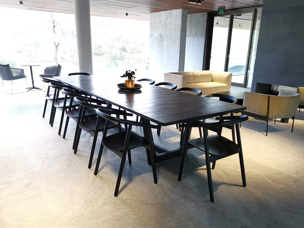 Eden Outdoor Table in ebonised timber - Nathan Day Design, full length view with dining chairs and centerpiece in lobby setting