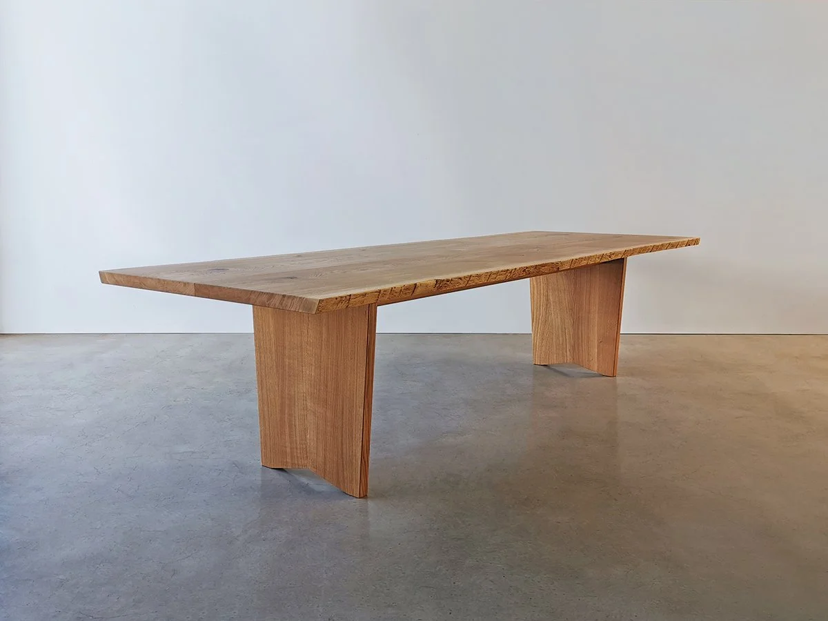 Live edge dining table in Tuart with honey-toned grain and slab-form legs, plain studio setting - bespoke furniture by Nathan Day Design