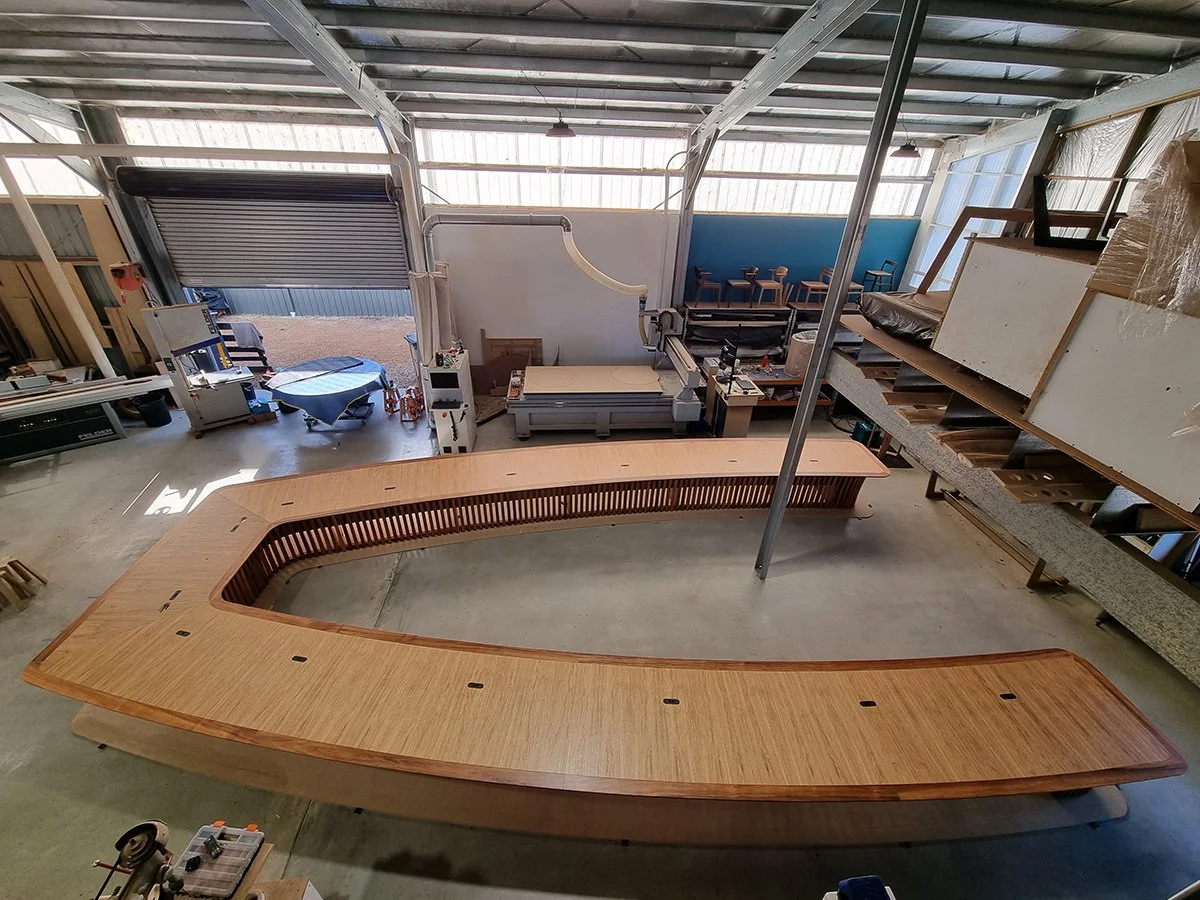 One - The Esplanade Boardroom Table in Australian Blackwood, fluted leg design - Nathan Day Design, overhead workshop view of elongated table under construction