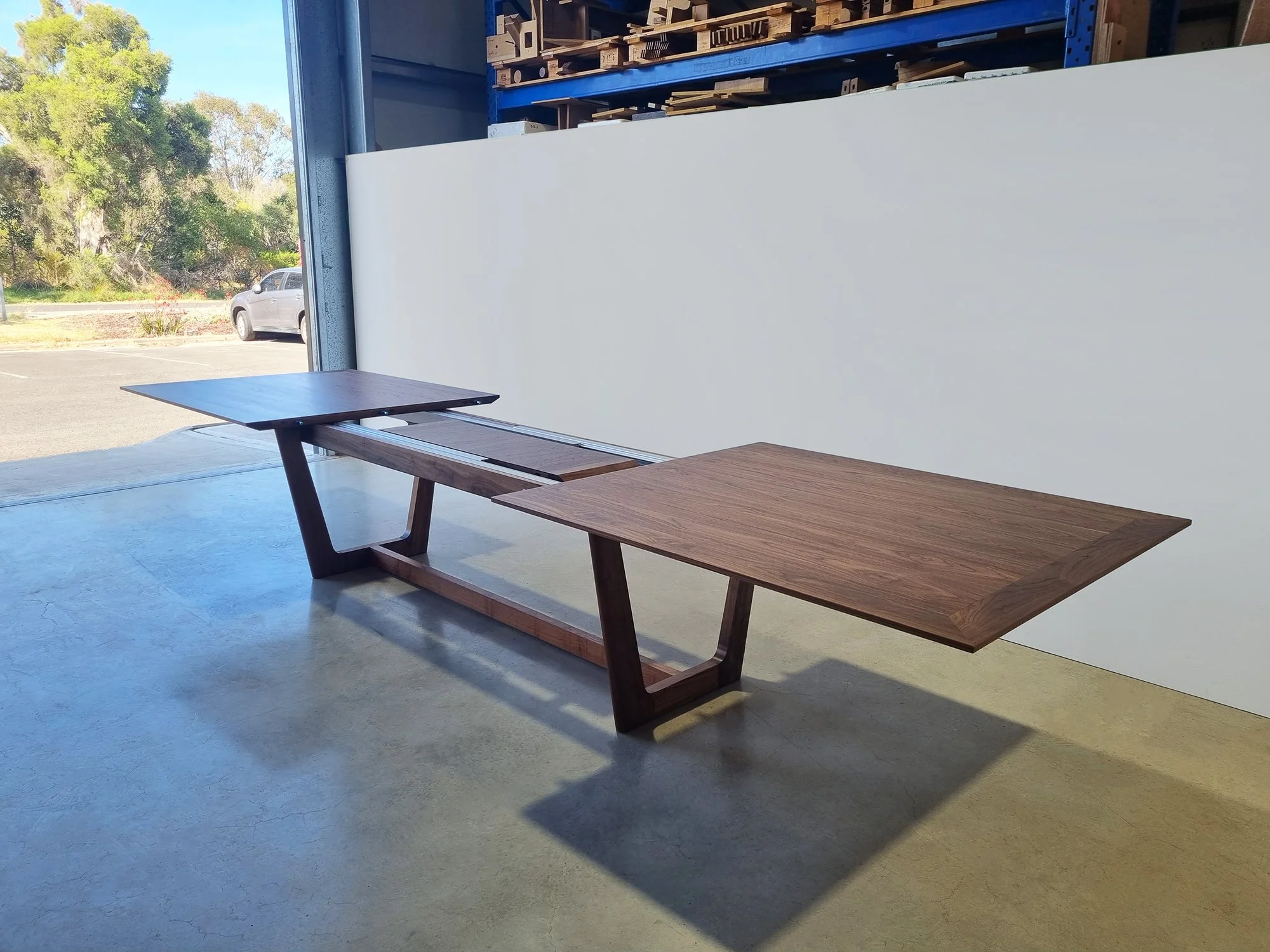 Botanical Table in Walnut shown extended with centre leaf insert revealing the extension mechanism, workshop doorway setting - bespoke furniture by Nathan Day Design