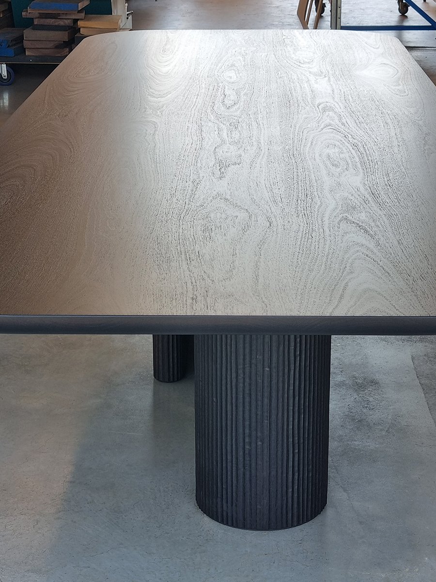 Detail of the Prehistoric Table's natural Jarrah top and ebonised textured cylindrical legs - Nathan Day Design