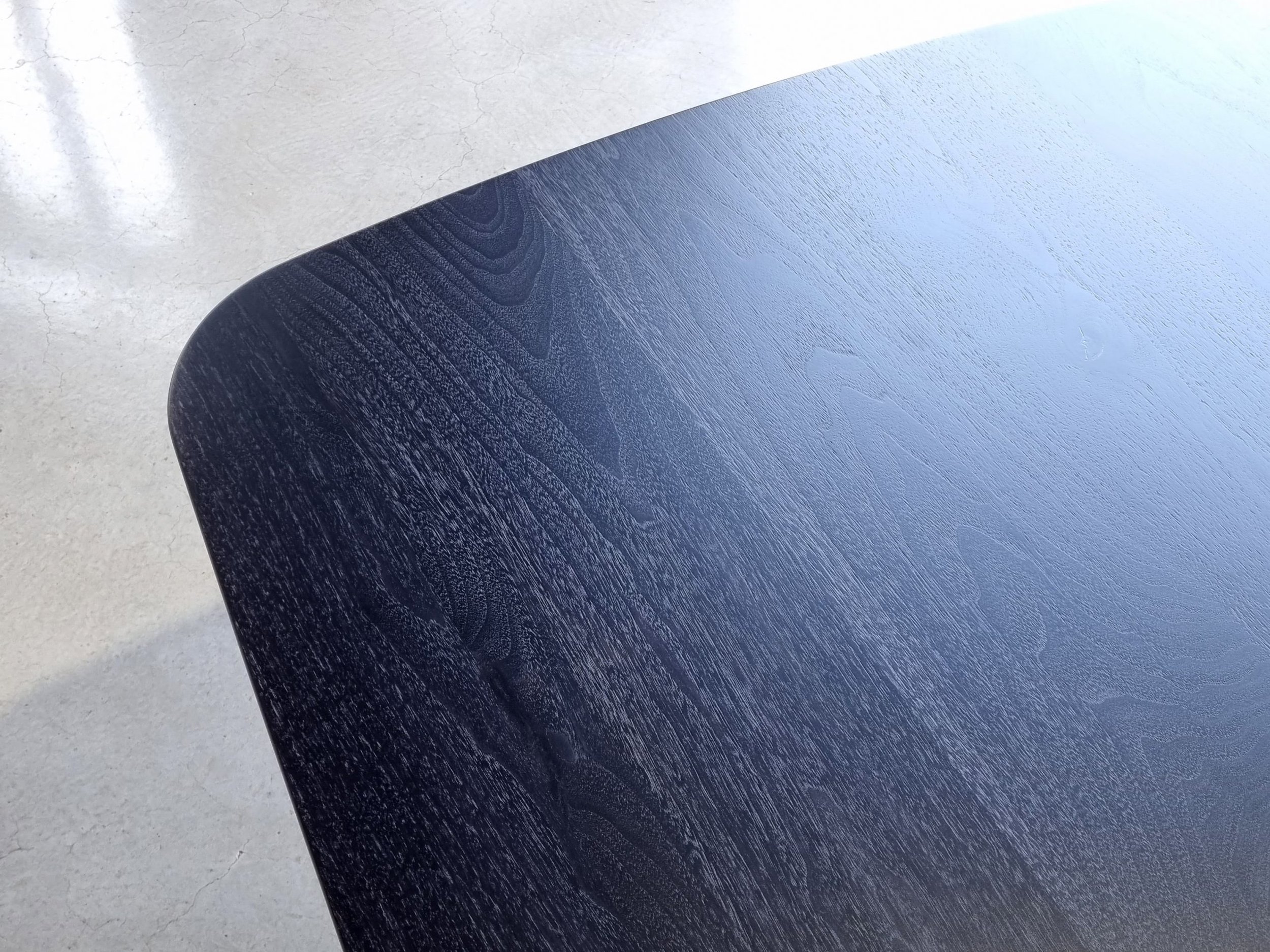Close-up of Column Table's Ebonised Walnut tabletop showing rich timber grain and rounded corner edge - bespoke furniture by Nathan Day Design