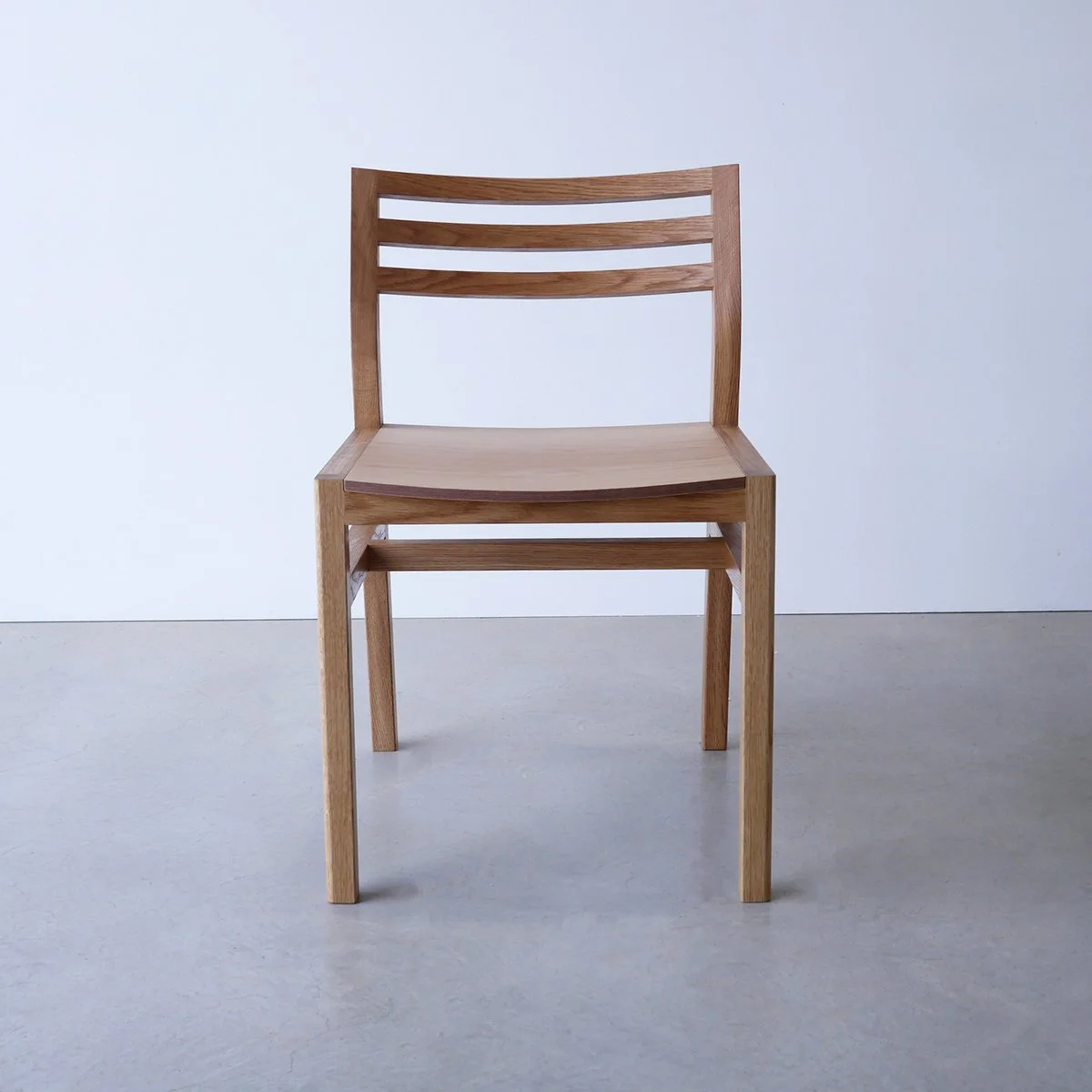 Front-on view of Walter Dining Chair in American Oak showing the horizontal slat backrest, plain studio setting - bespoke furniture by Nathan Day Design