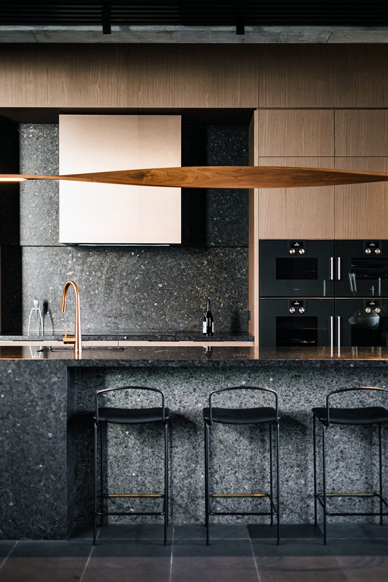 Ernest Pendant Light in Ash, elongated blade-form design - Nathan Day Design, installed above stone kitchen island with bar stools