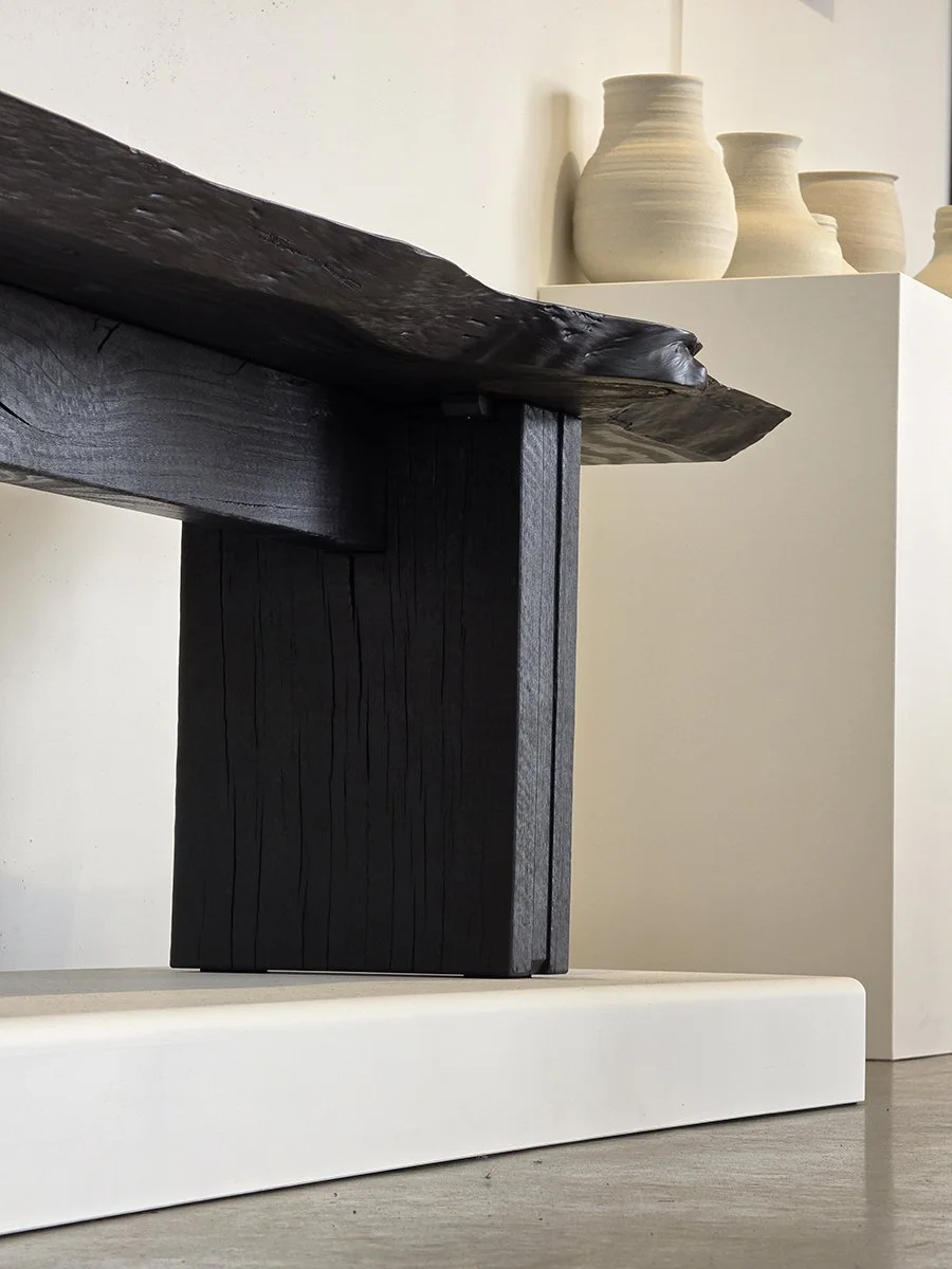 Burnside Bench end detail in scorched Jetty Jarrah displayed on a plinth beside a collection of ceramic vessels - bespoke seating by Nathan Day Design