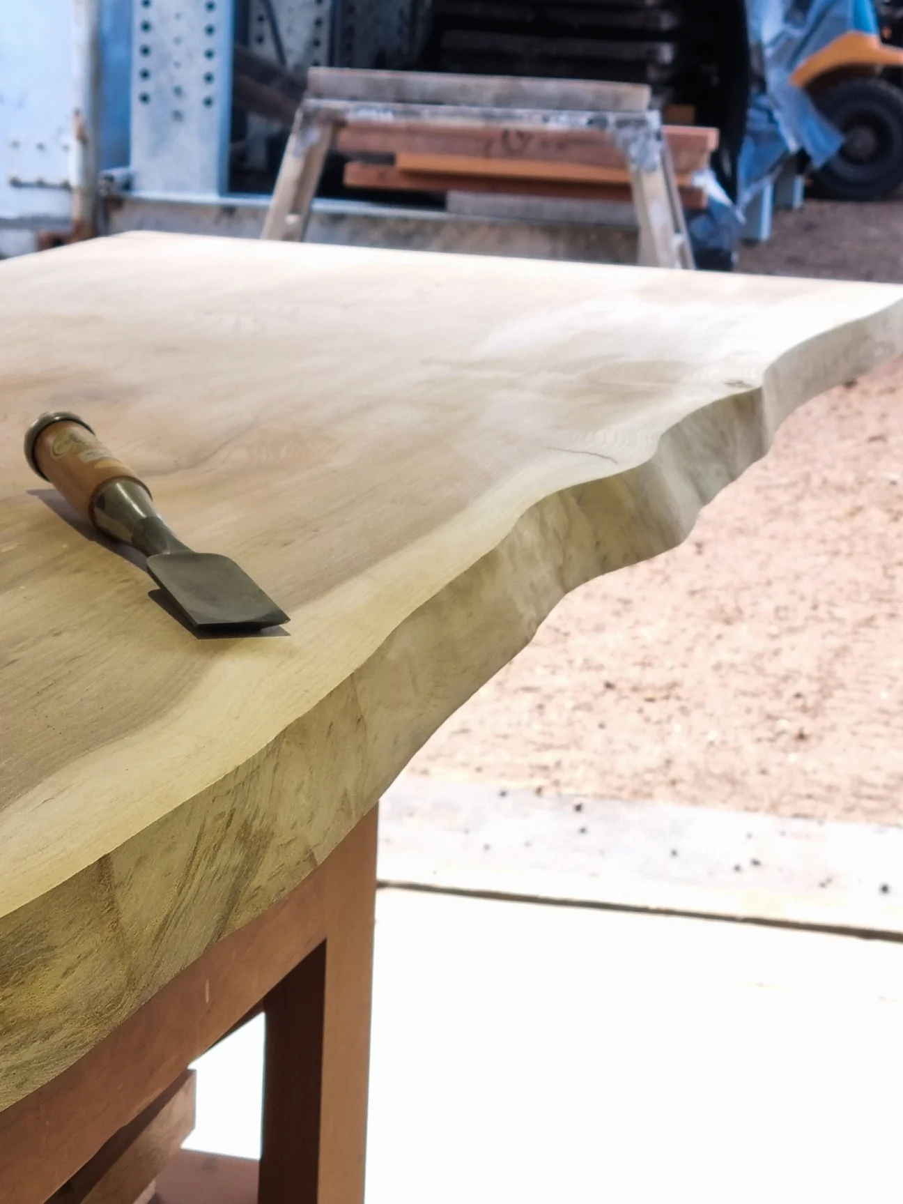 Hand tool resting on a live-edge timber slab being finished at Nathan Day Design