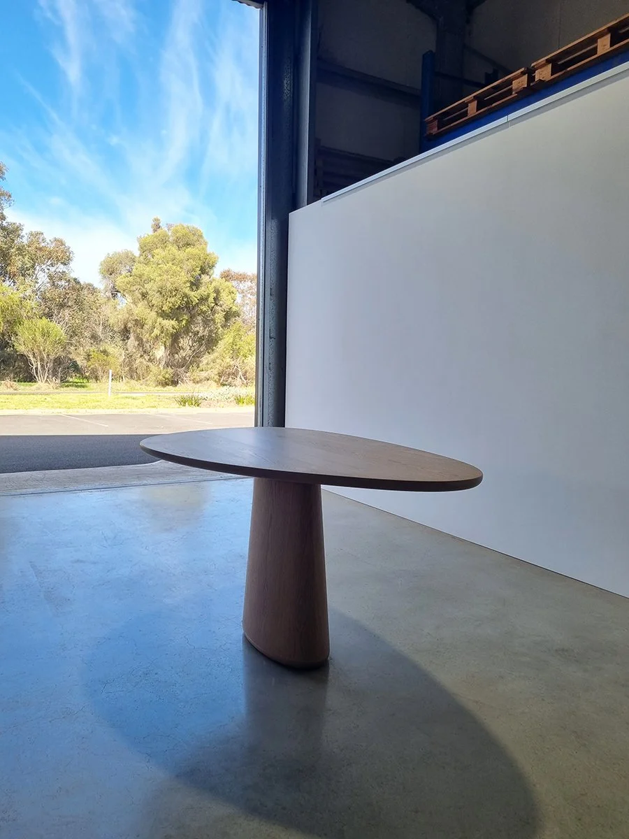 Pebble Table in Walnut with organic tapered pedestal, positioned near open workshop doorway with bushland view - bespoke furniture by Nathan Day Design