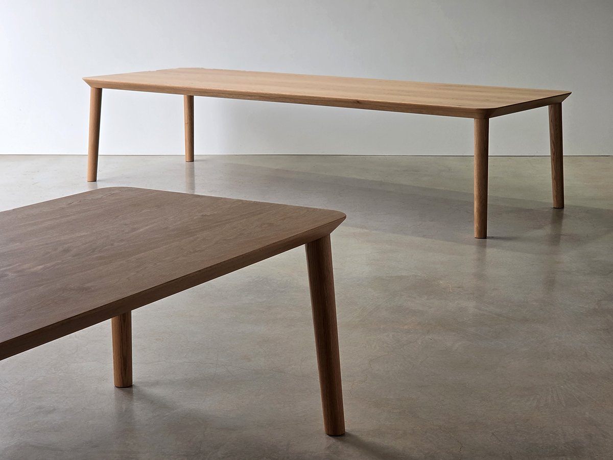 Mercator Way Table in American Oak shown in plain studio setting alongside a darker timber tabletop in foreground, showcasing timber tone contrast - bespoke furniture by Nathan Day Design
