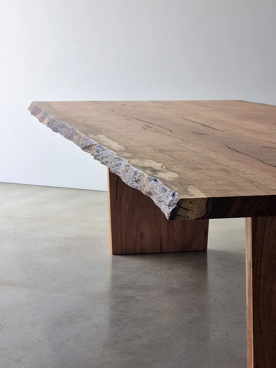 Live edge dining table in Marri with raw untouched bark preserved along the corner edge, plain studio setting - bespoke furniture by Nathan Day Design