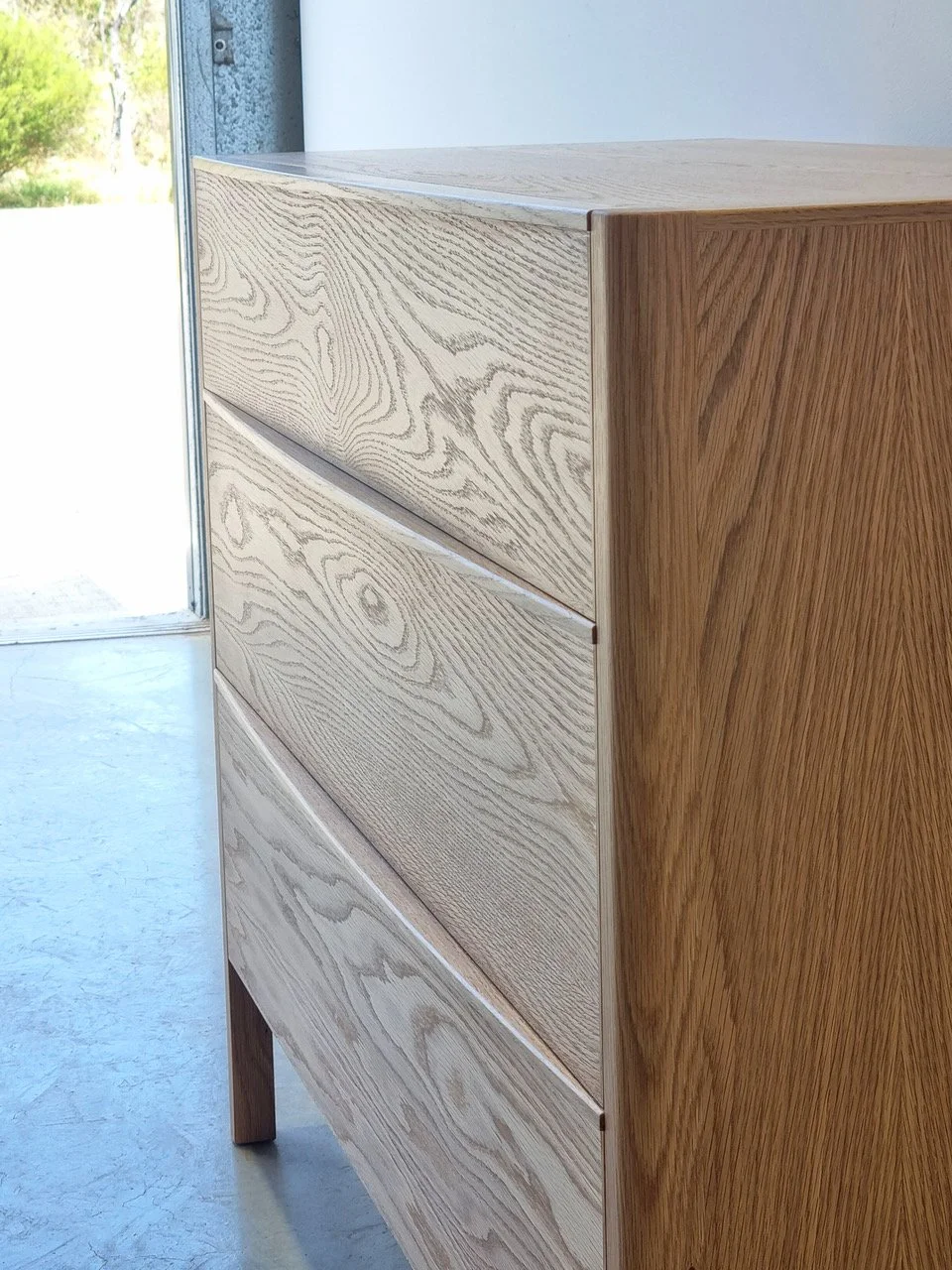 Hampden Chest of Drawers in American Oak - Nathan Day Design, angled corner view near window in lighter finish