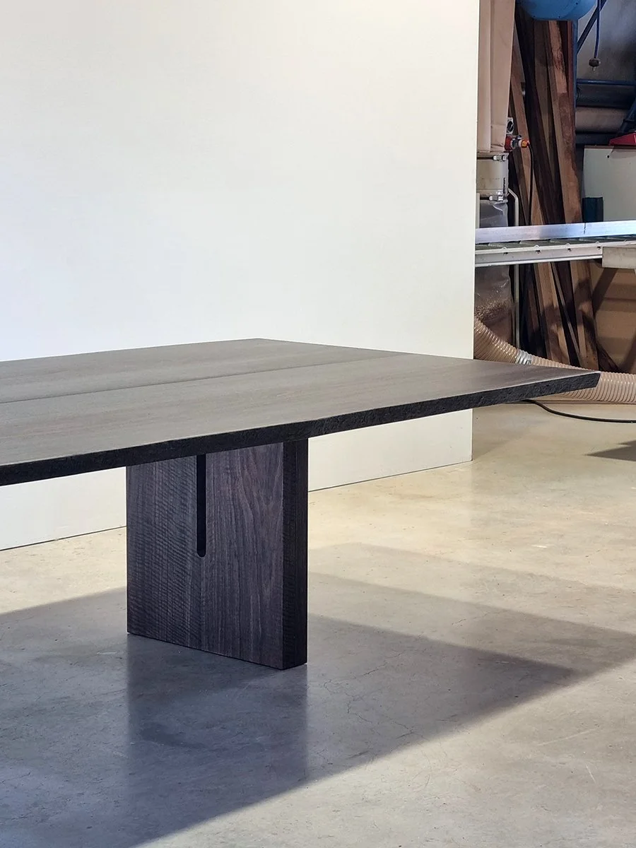 Live edge dining table in Ebonised Jarrah with solid block leg base, workshop setting - bespoke furniture by Nathan Day Design